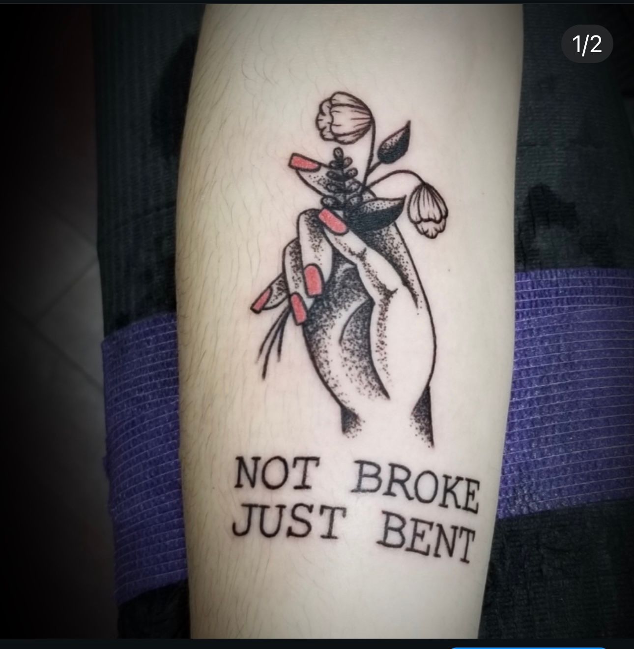 A tattoo of a hand holding flowers that says not broke just bent