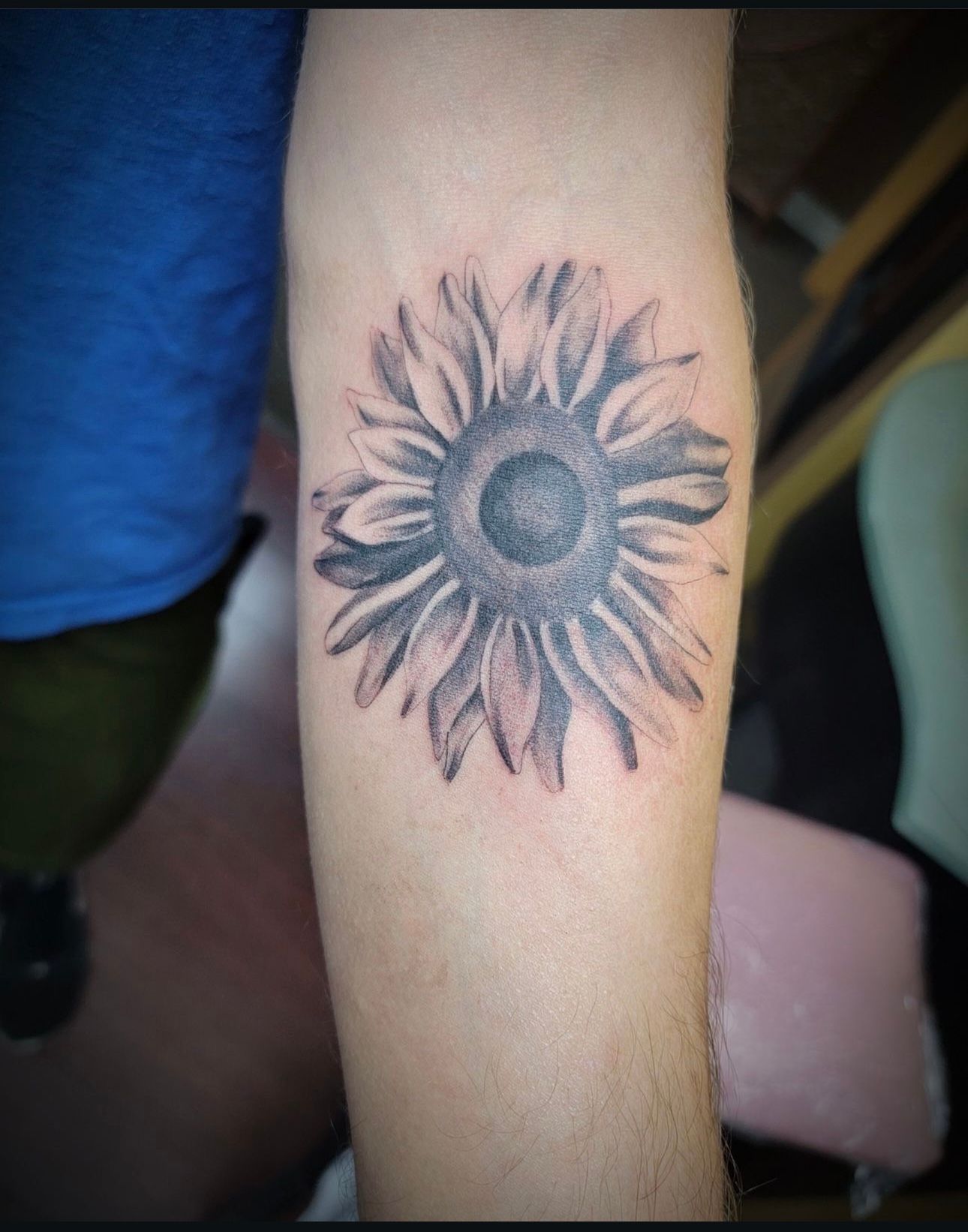 A man has a tattoo of a sunflower on his forearm