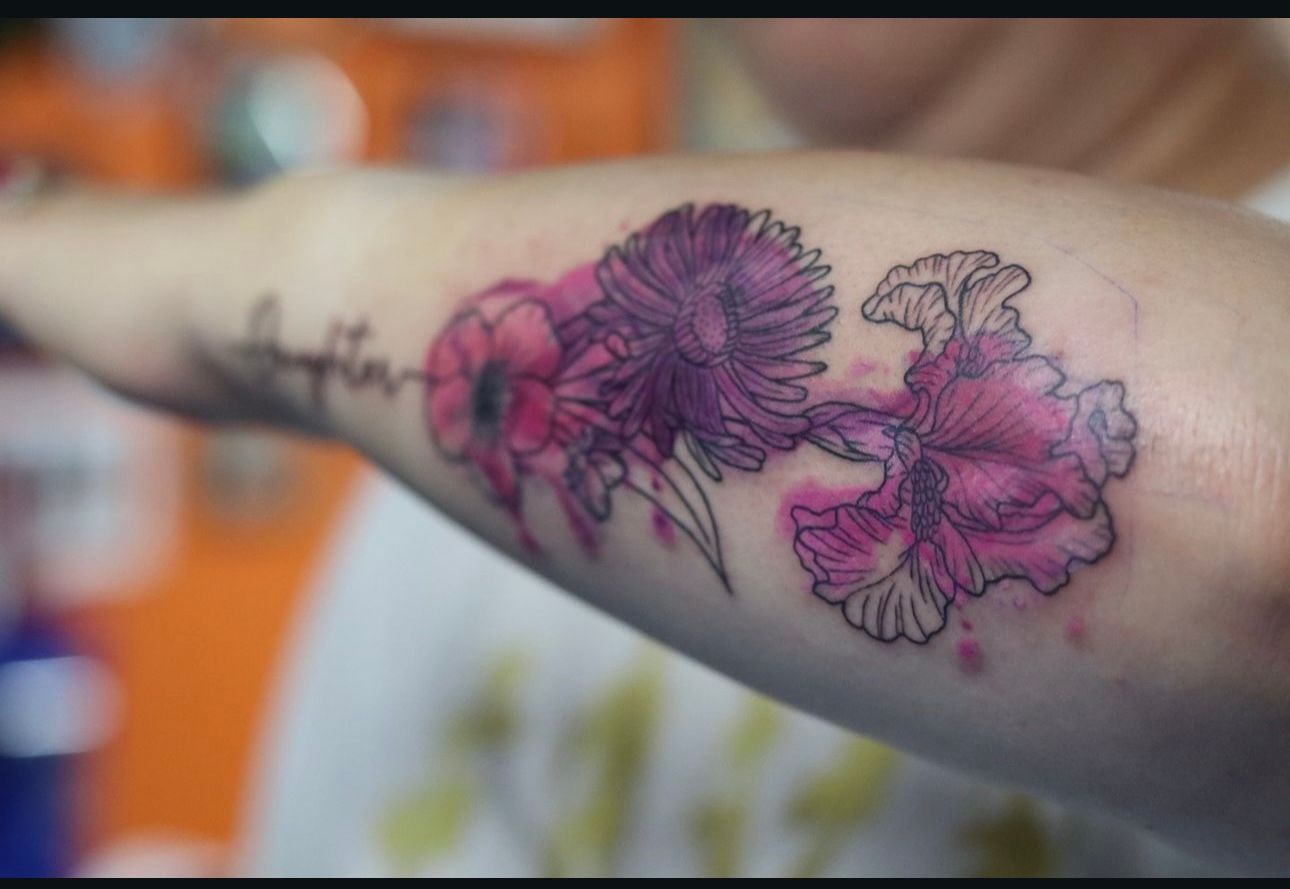 A woman has a tattoo of purple flowers on her arm