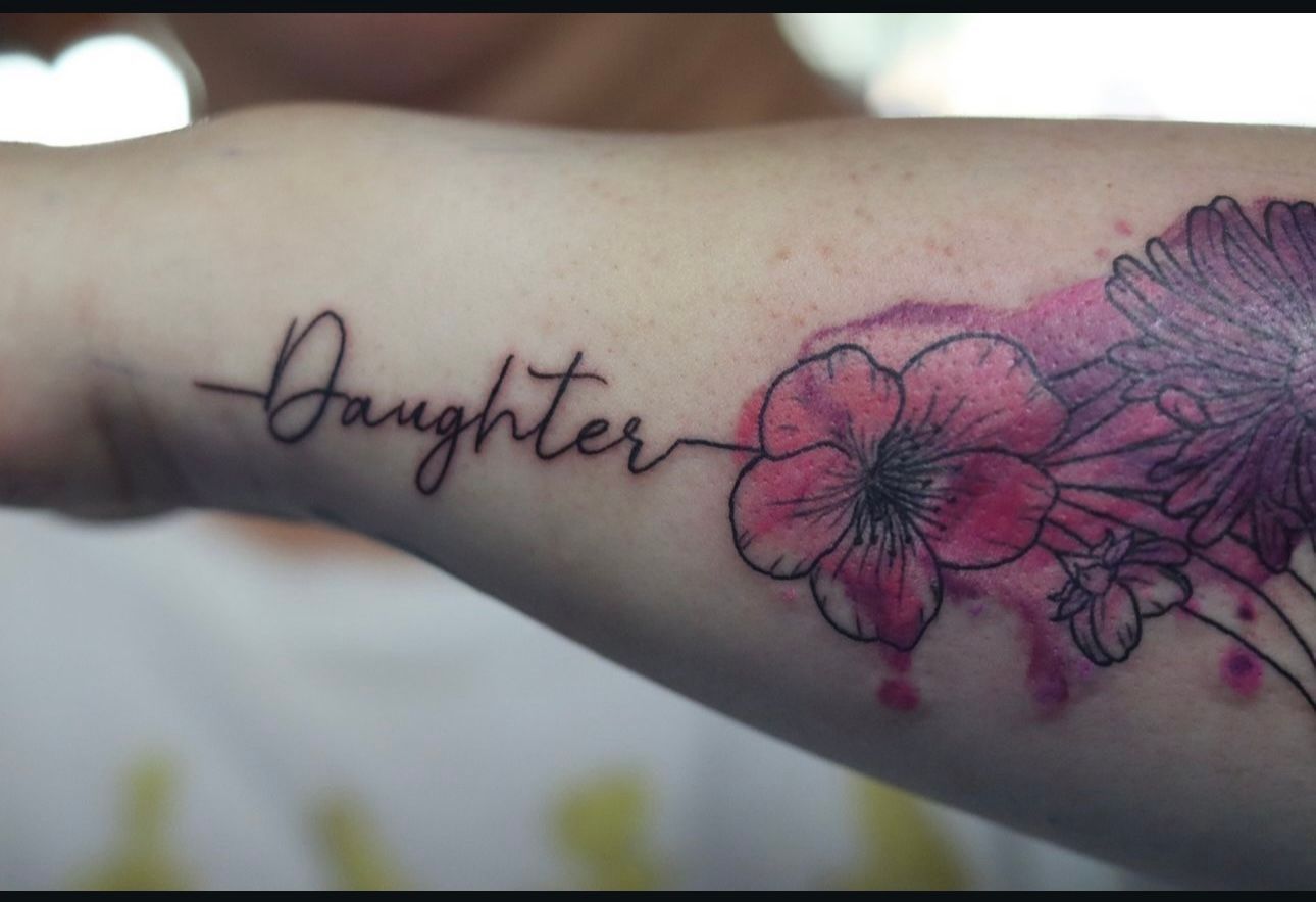 A woman has a tattoo on her arm that says daughter