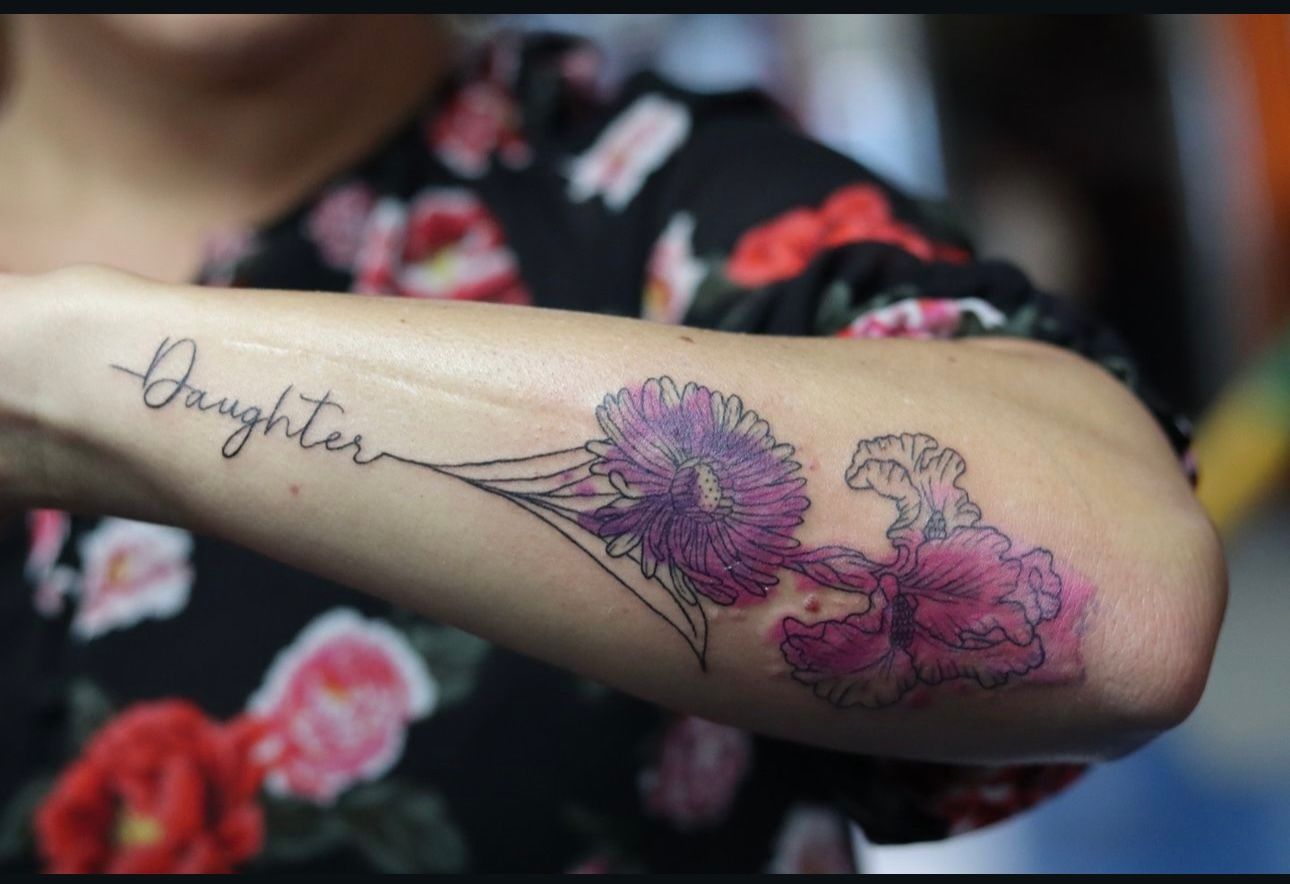 A woman has a tattoo on her arm that says daughter