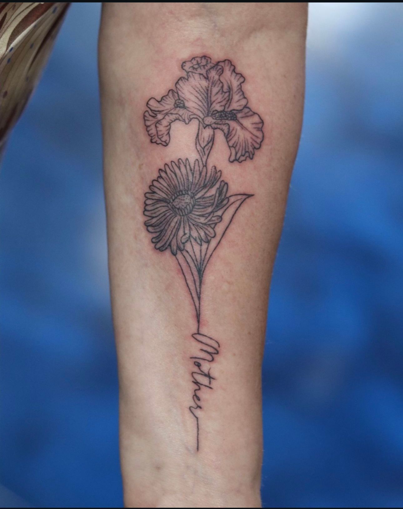 A tattoo of a flower with the word mother on it
