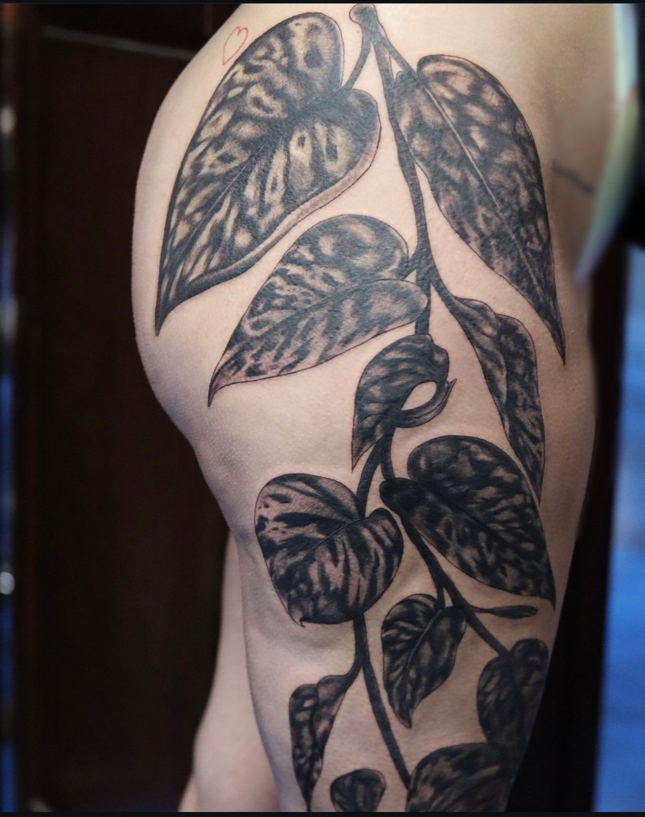 A woman has a tattoo of leaves on her thigh