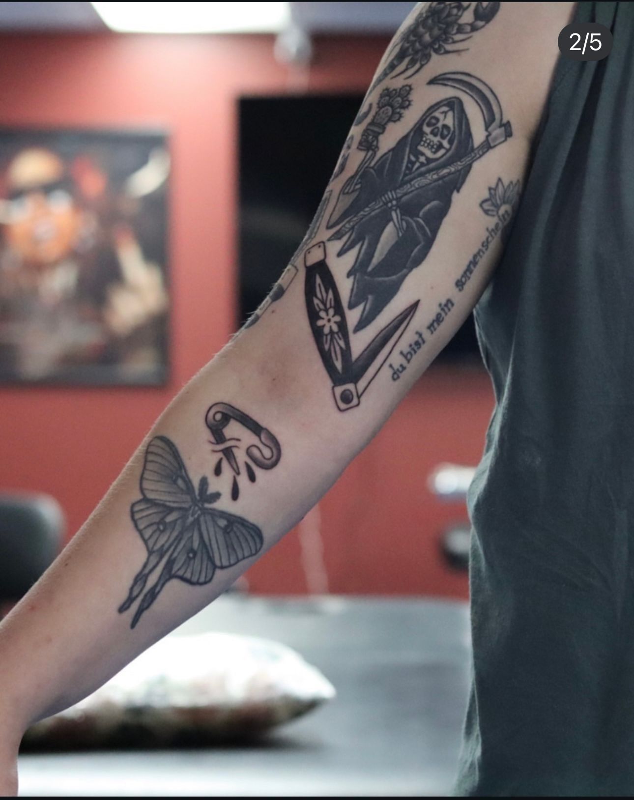 A man has a tattoo of a reaper and a butterfly on his arm