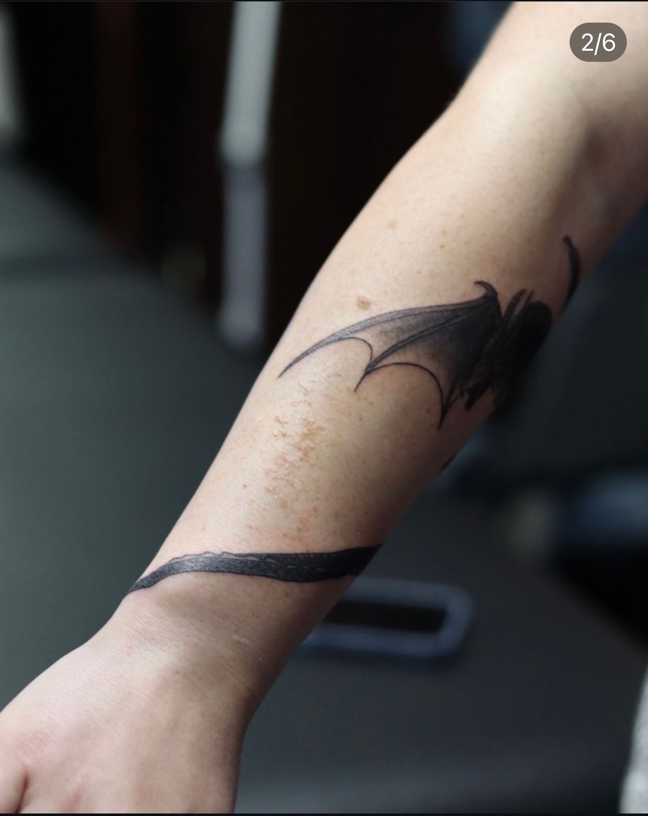 A person has a tattoo of a bat on their forearm