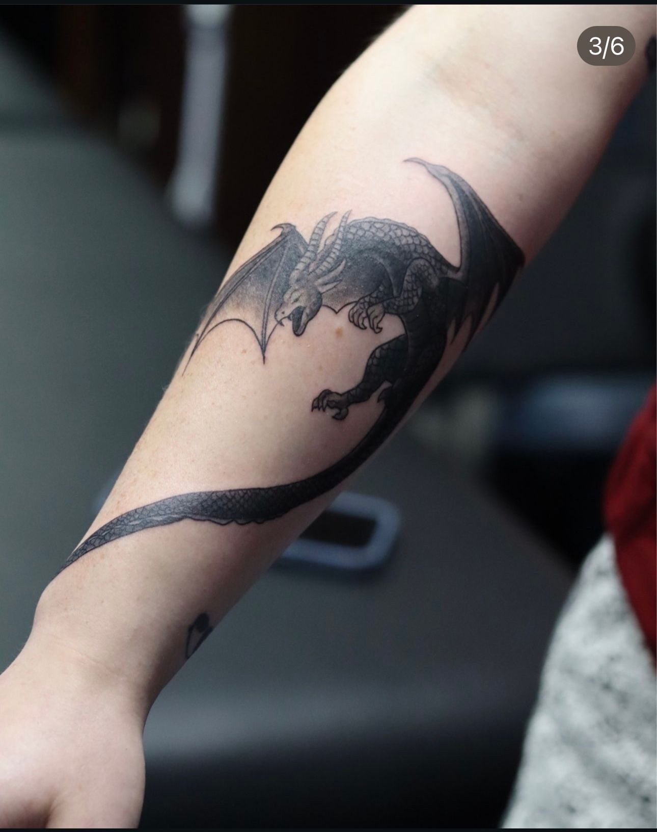 A person has a tattoo of a dragon on their arm