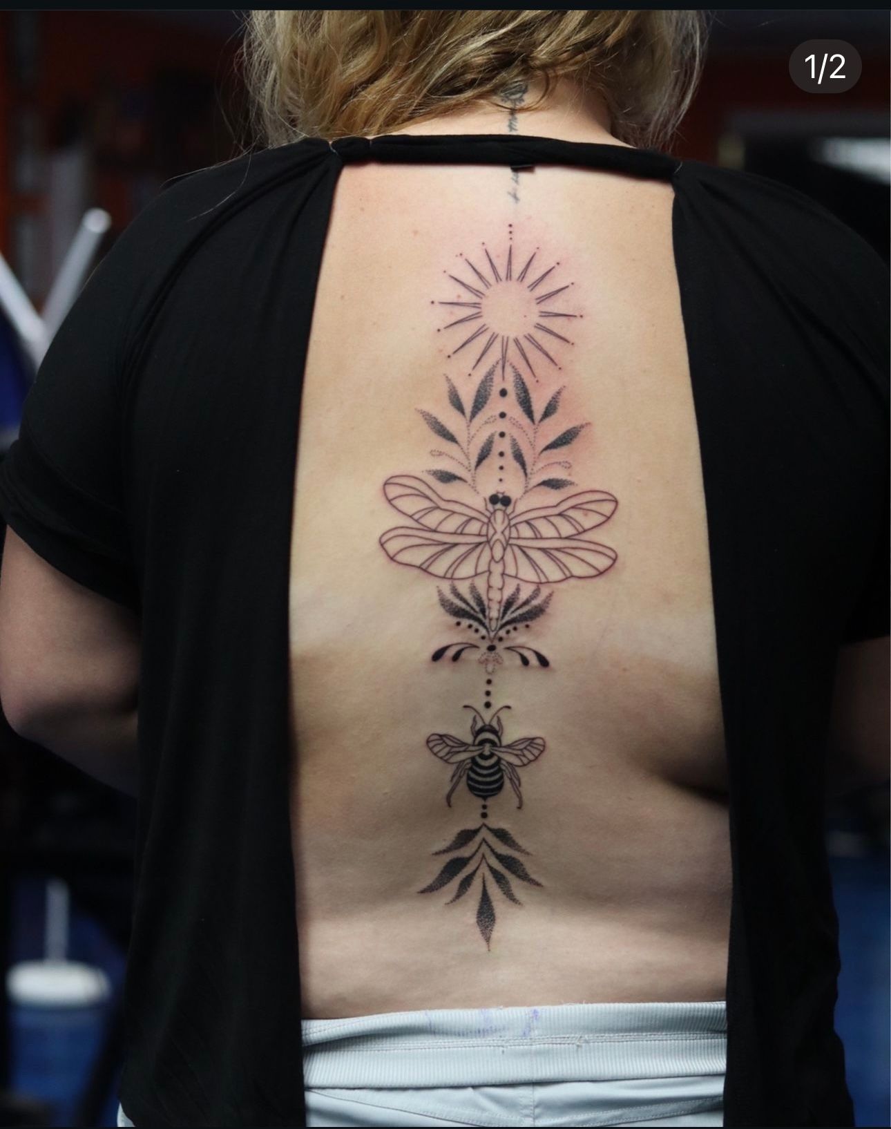 A woman has a tattoo of bees and leaves on her back.