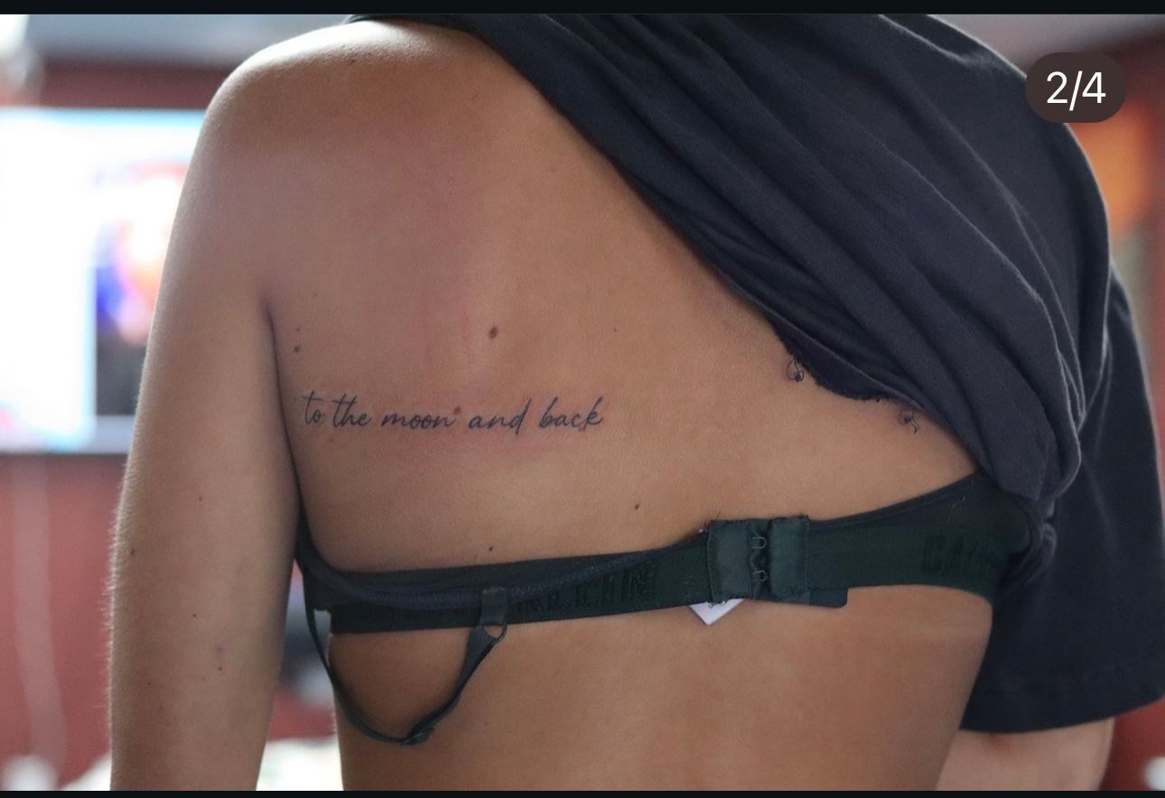 A woman has a tattoo on her back that says to the moon and back