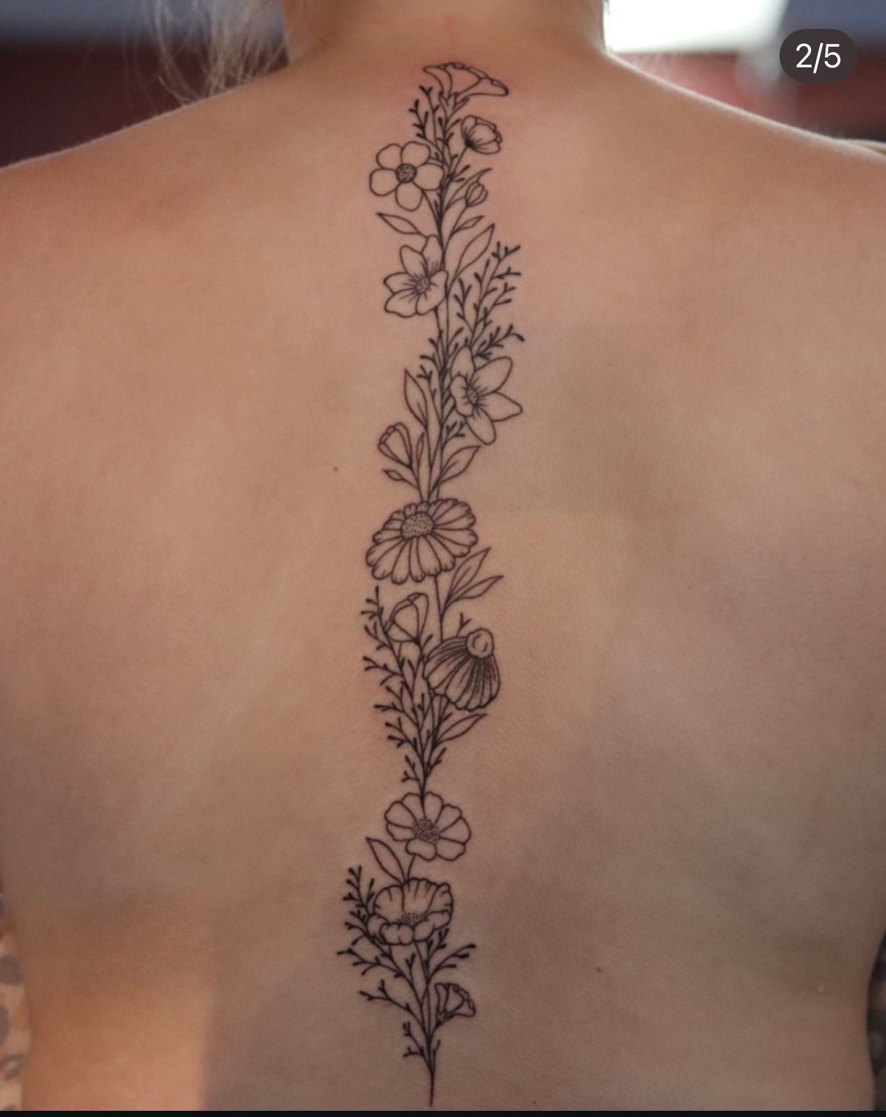 A woman has a tattoo of flowers on her back