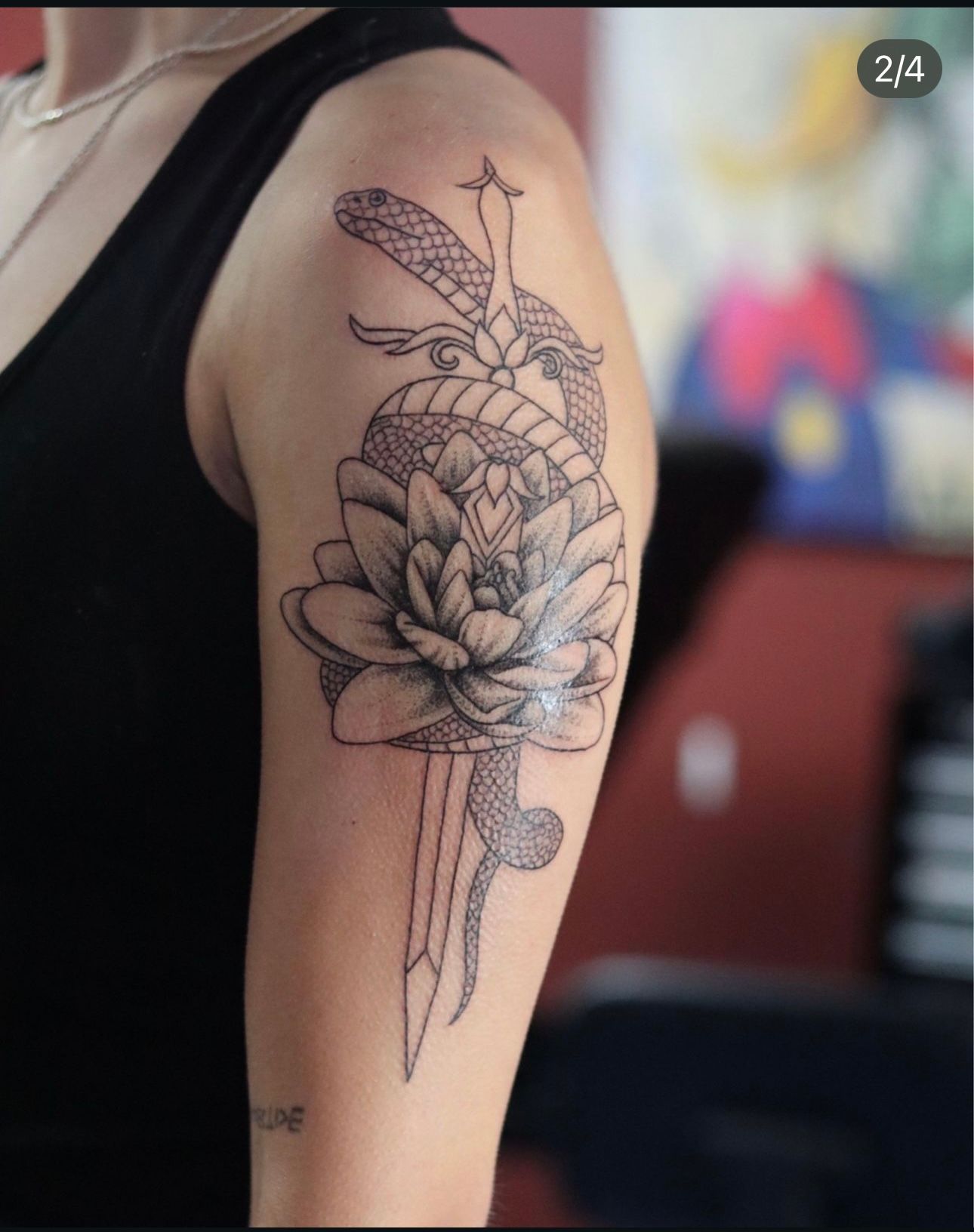 A woman has a tattoo of a snake and a flower on her arm