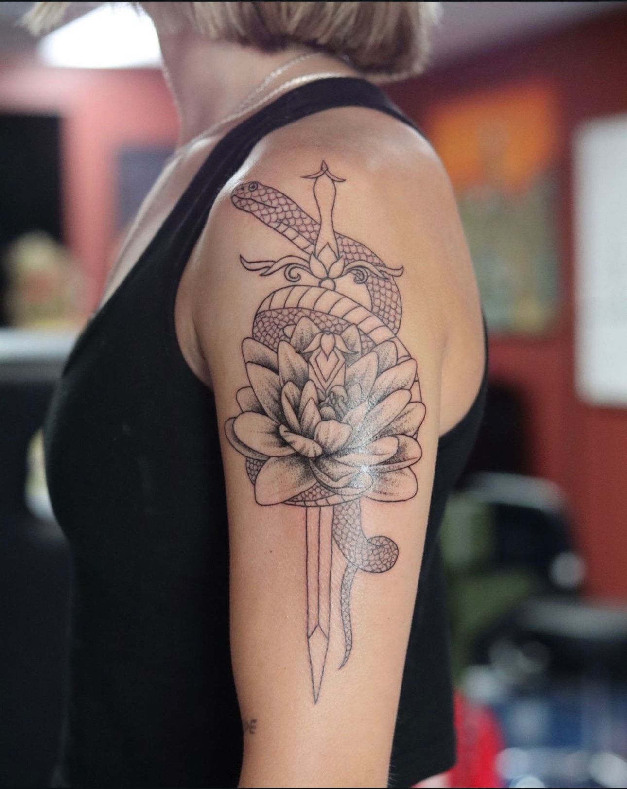 A woman has a tattoo of a snake and a flower on her arm