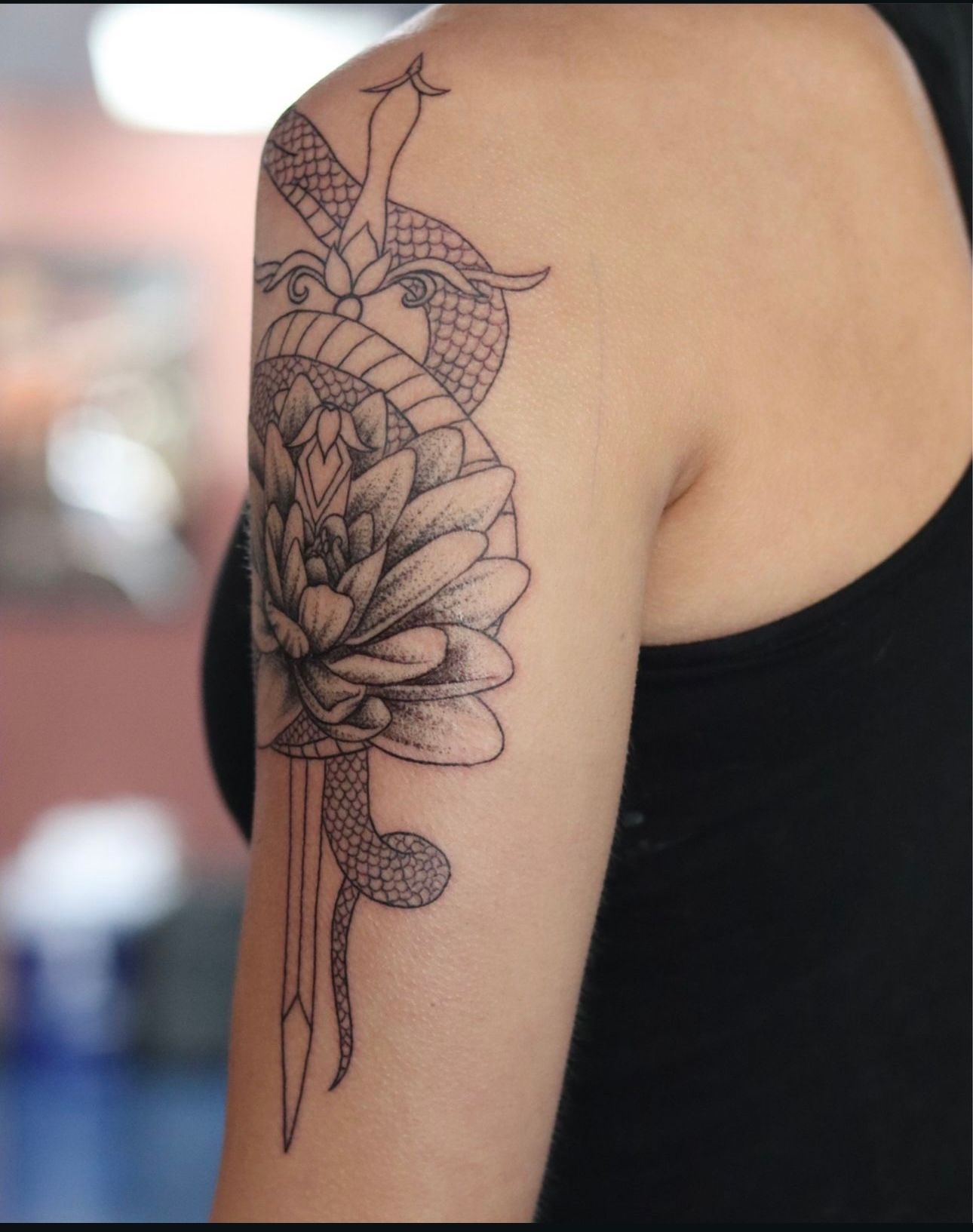 A woman has a tattoo of a snake and a flower on her arm
