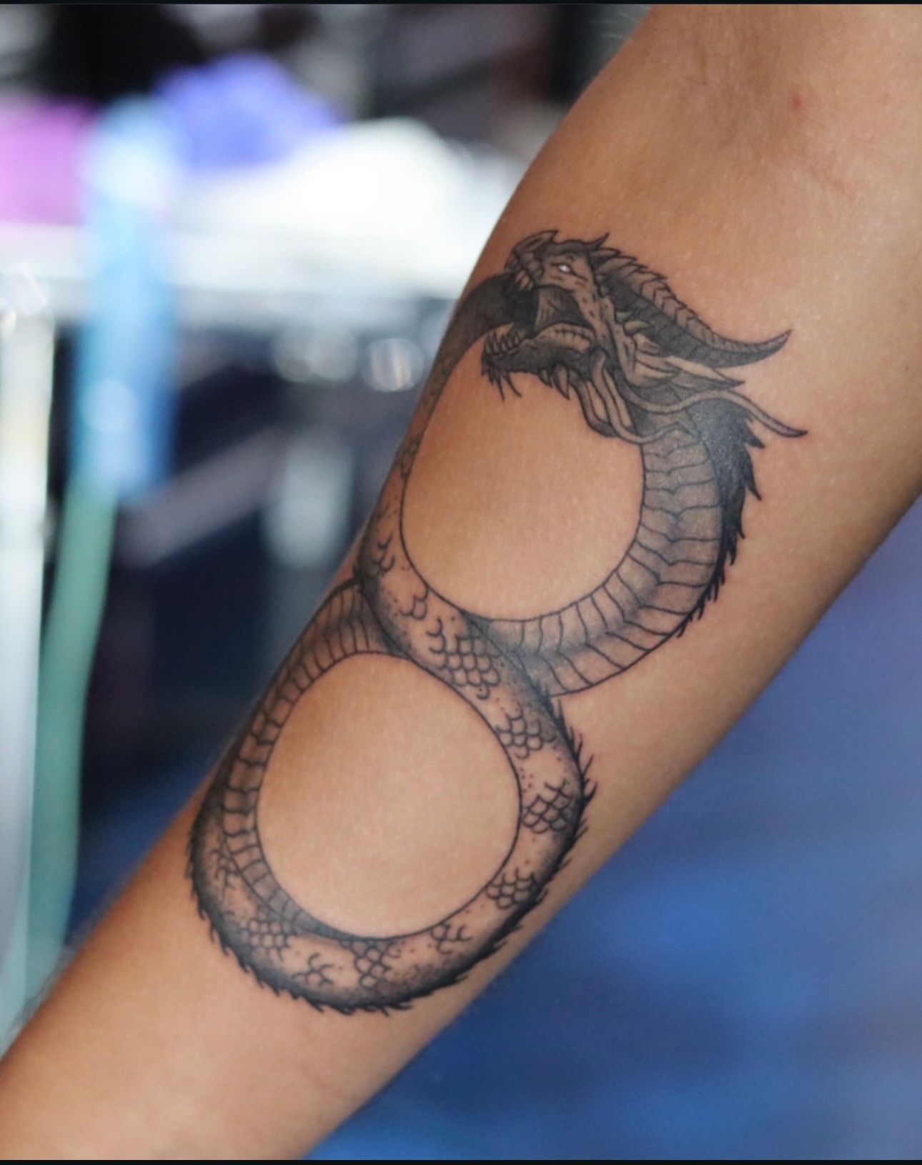 A person has a tattoo of a dragon on their arm