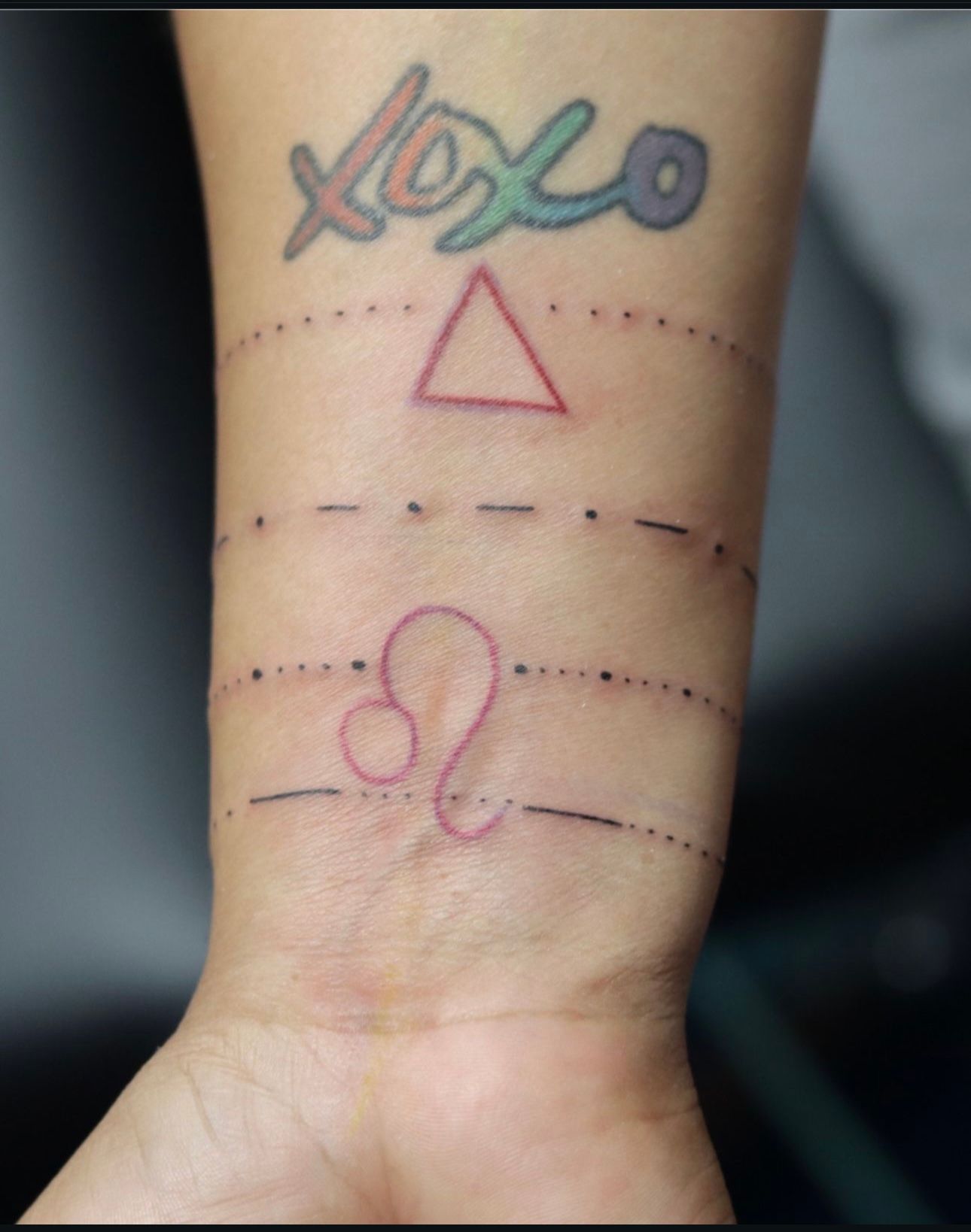 A person has a tattoo on their wrist that says xoxo