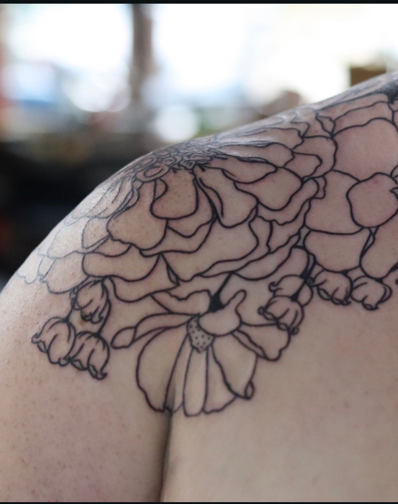 A woman has a tattoo of flowers on her shoulder