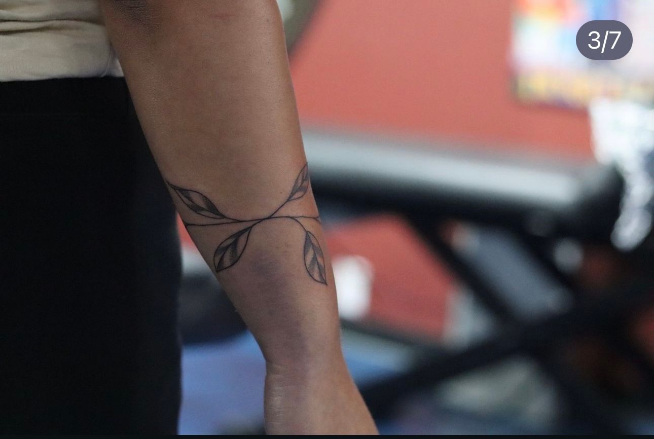A woman has a tattoo of leaves on her wrist
