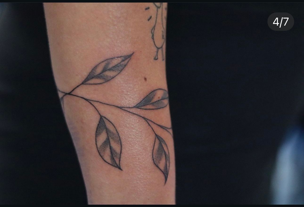 A person has a tattoo of leaves on their arm