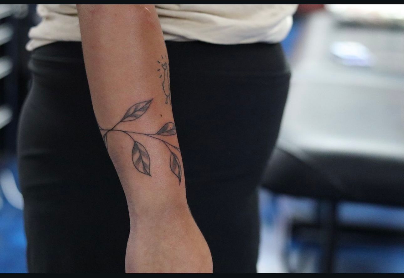 A woman has a tattoo of leaves on her forearm