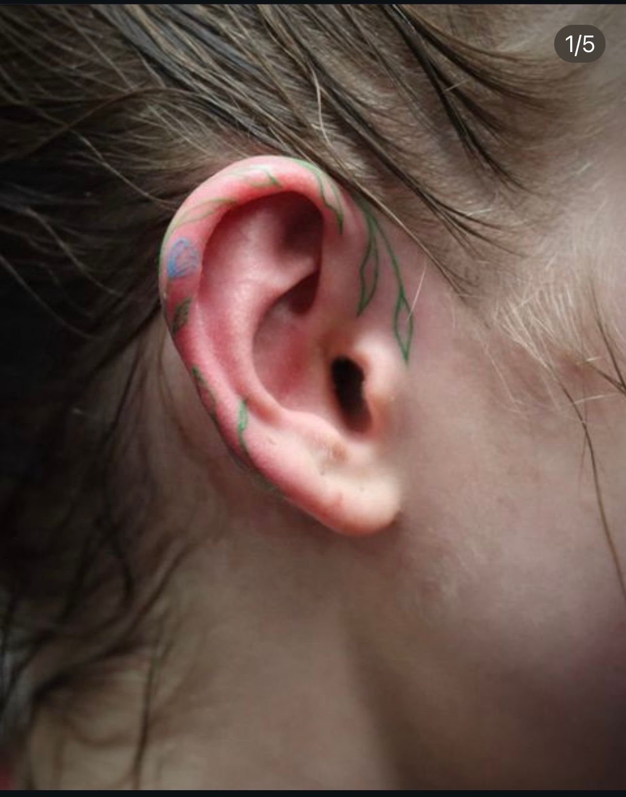 A close up of a person 's ear with a tattoo on it.