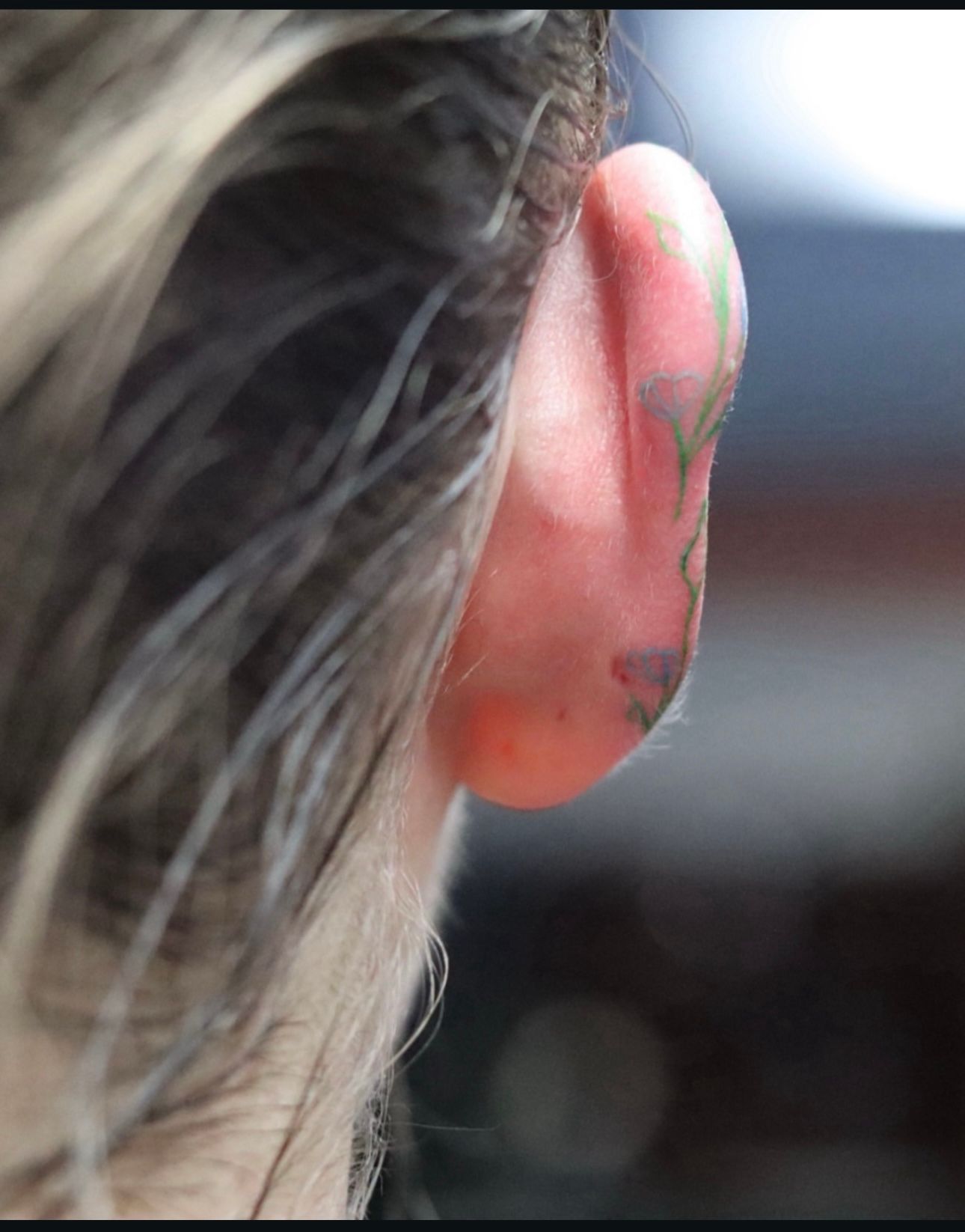 A close up of a person 's ear with a tattoo on it