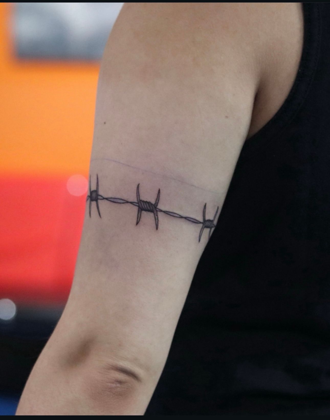 A person has a barbed wire tattoo on their arm