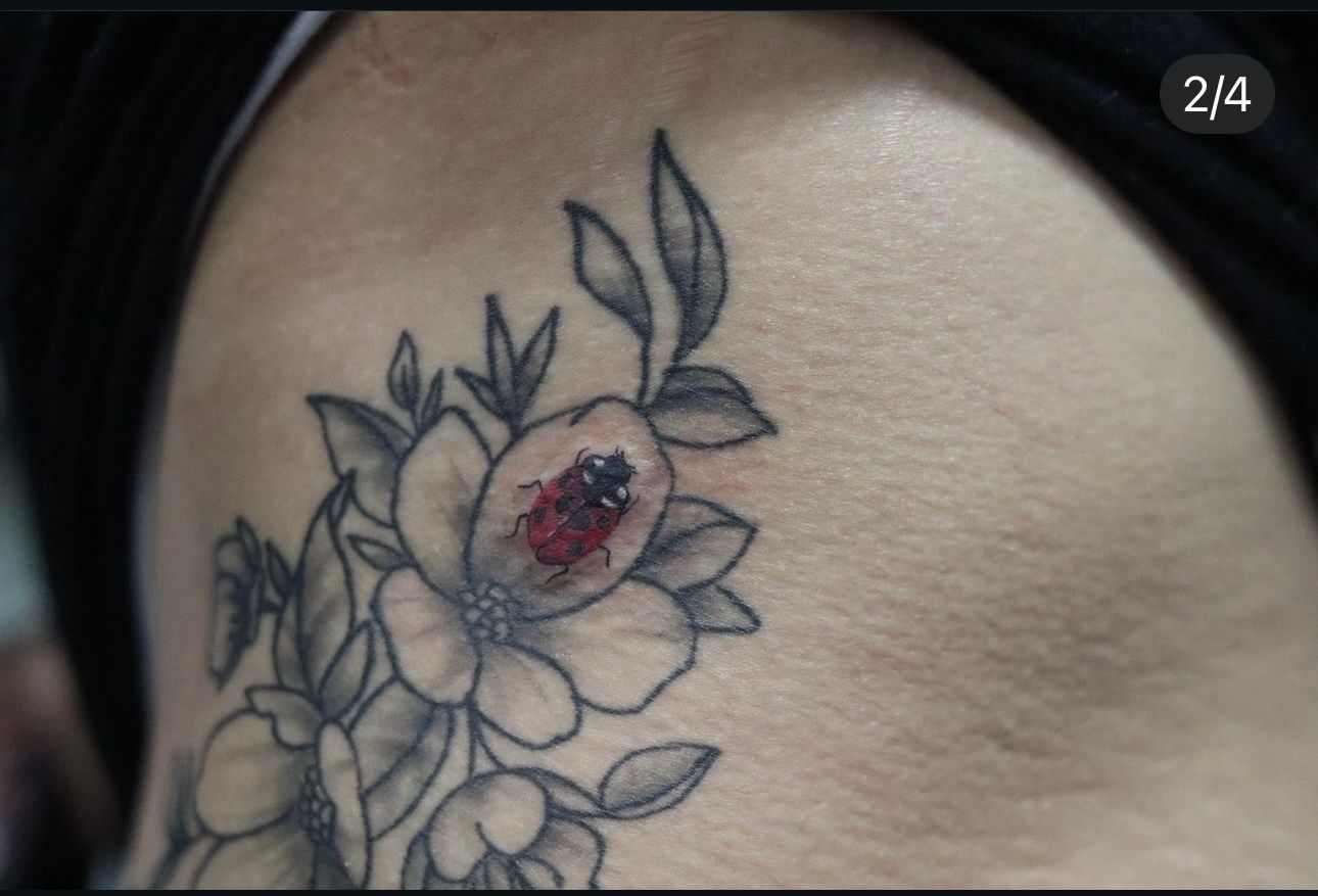 A ladybug is sitting on a flower in a tattoo