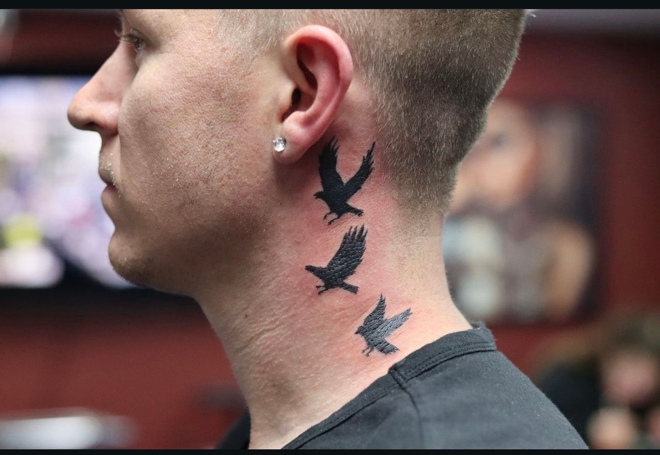 A man has three birds tattooed on his neck