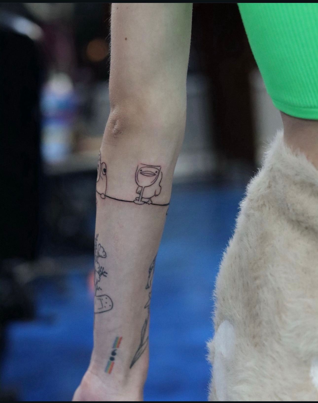 A woman has a tattoo of a cup on her arm