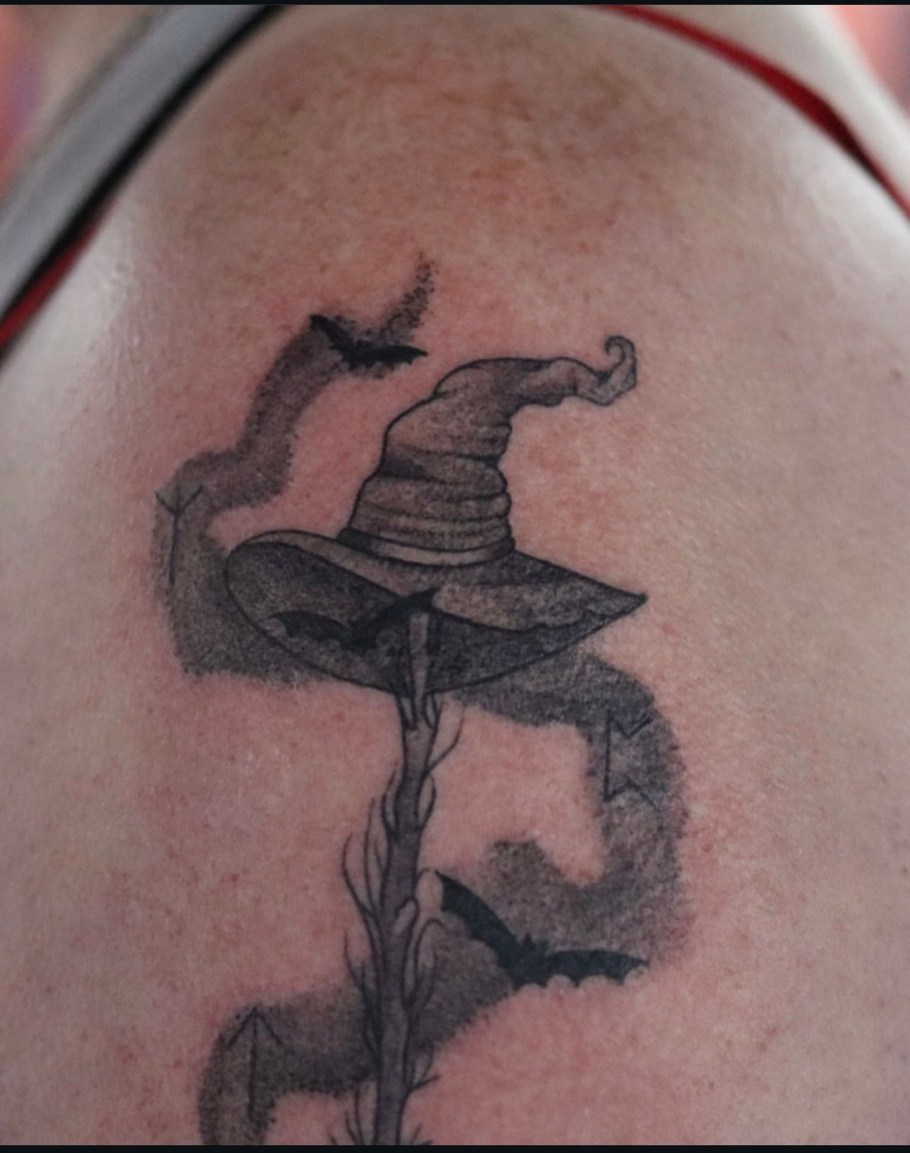 A woman has a tattoo of a witch hat on her back