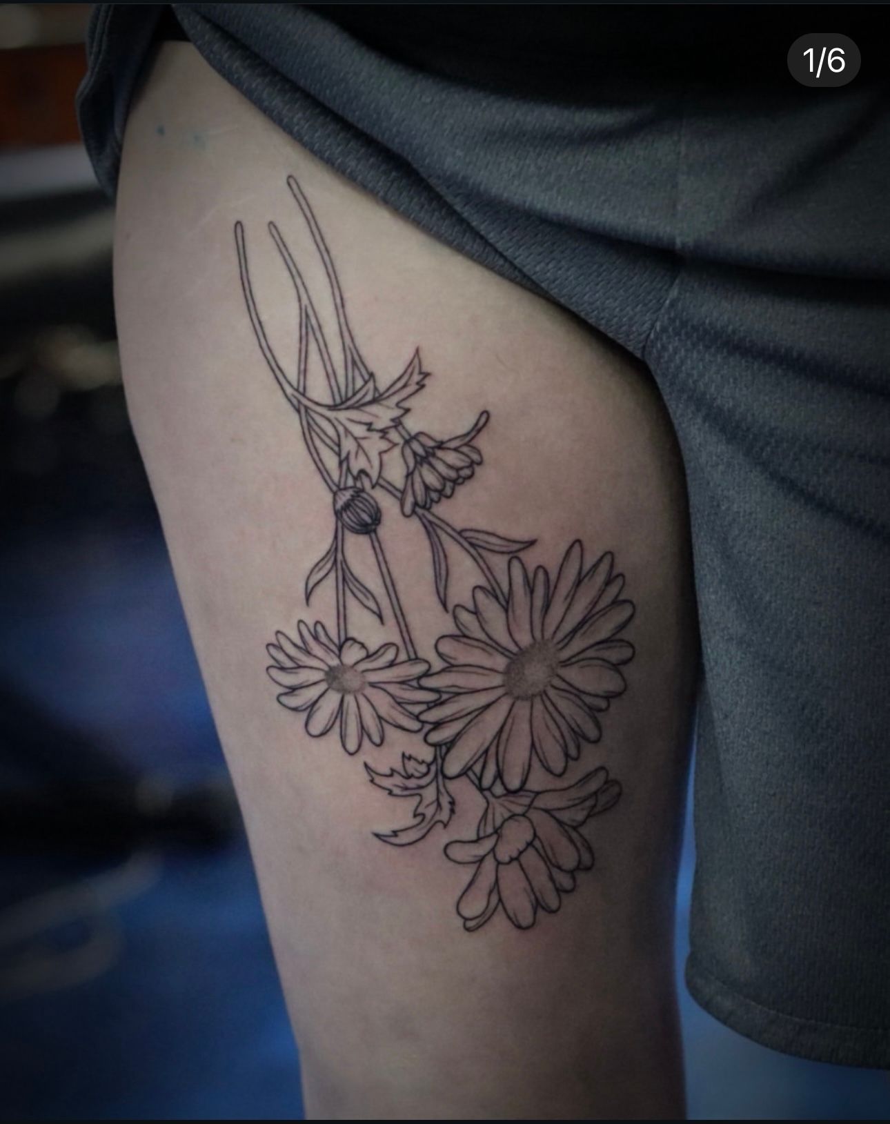 A woman has a tattoo of daisies on her thigh