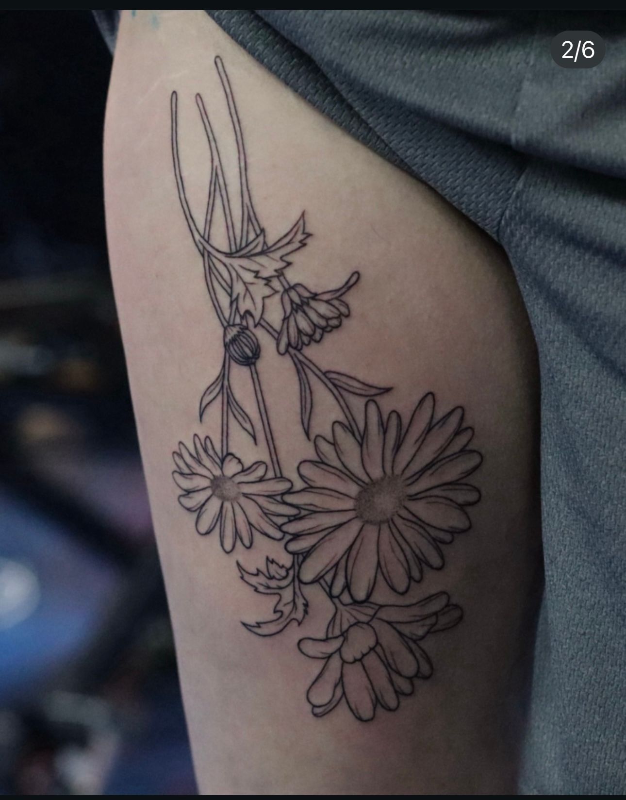 A person has a tattoo of daisies on their thigh
