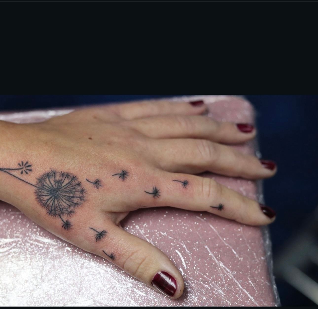 A woman has a dandelion tattoo on her hand
