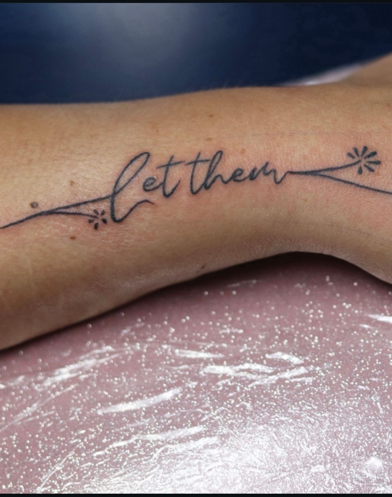 A woman has a tattoo on her wrist that says let them