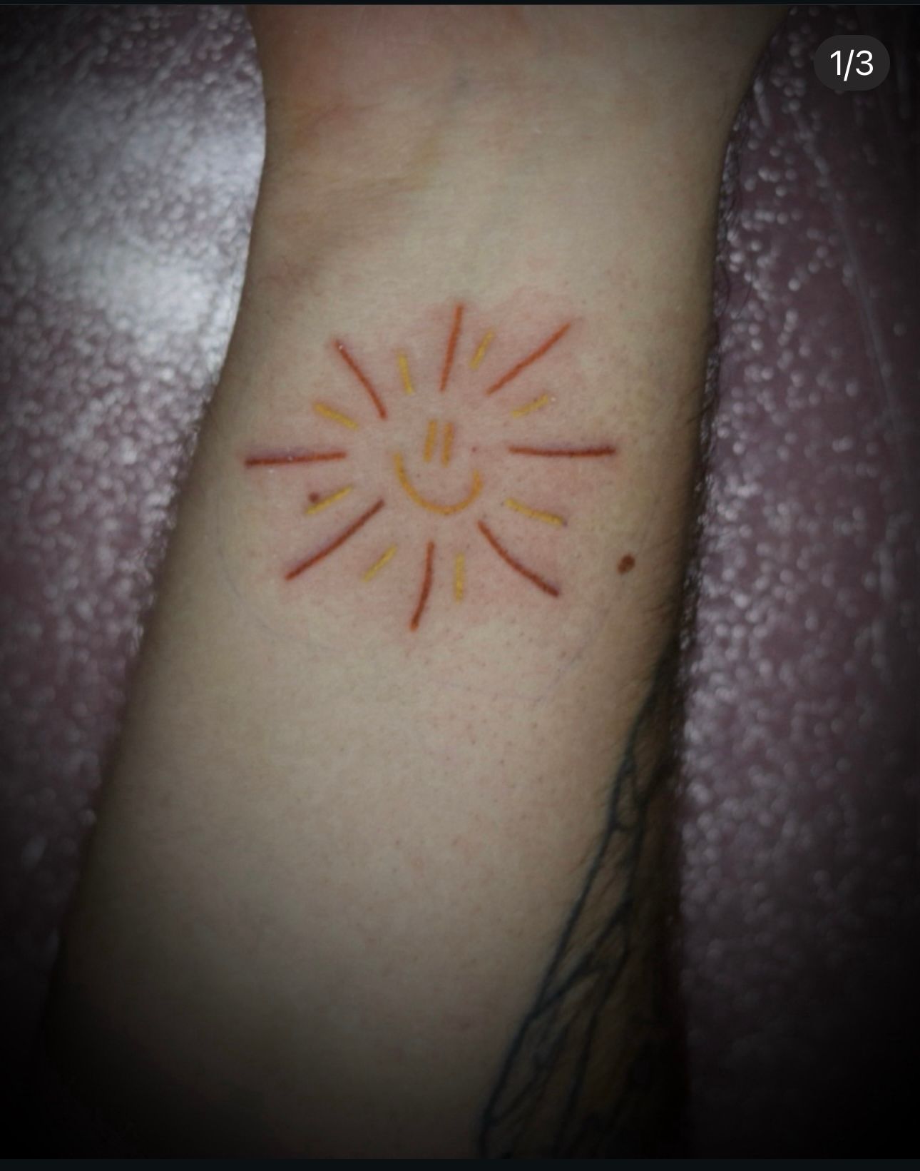 A person has a tattoo of a sun on their wrist