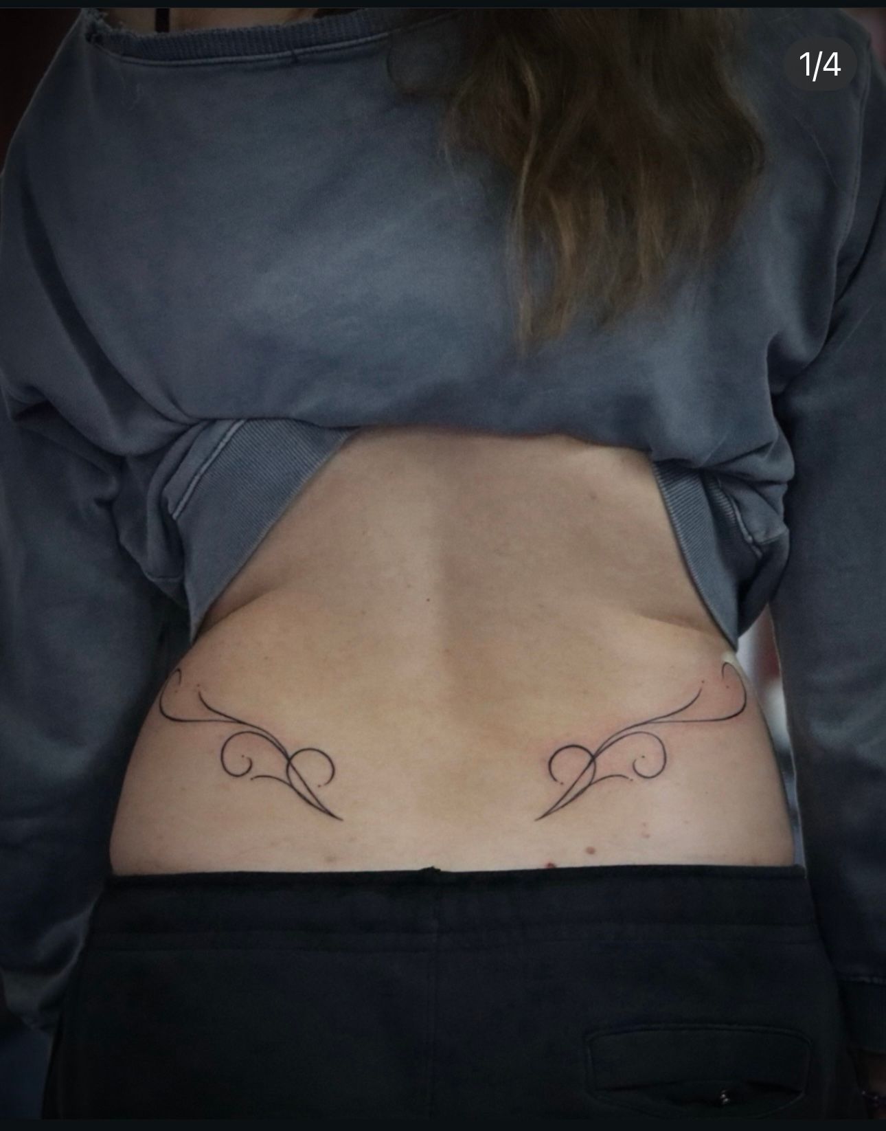 The back of a woman with a tattoo on her lower back.