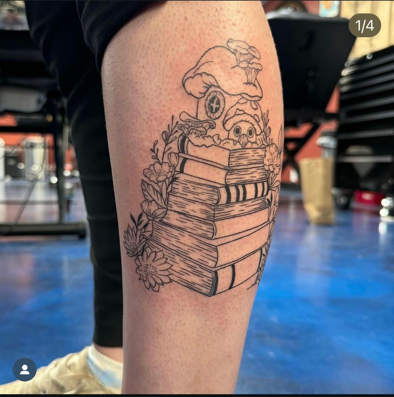 A person has a tattoo of a stack of books on their leg