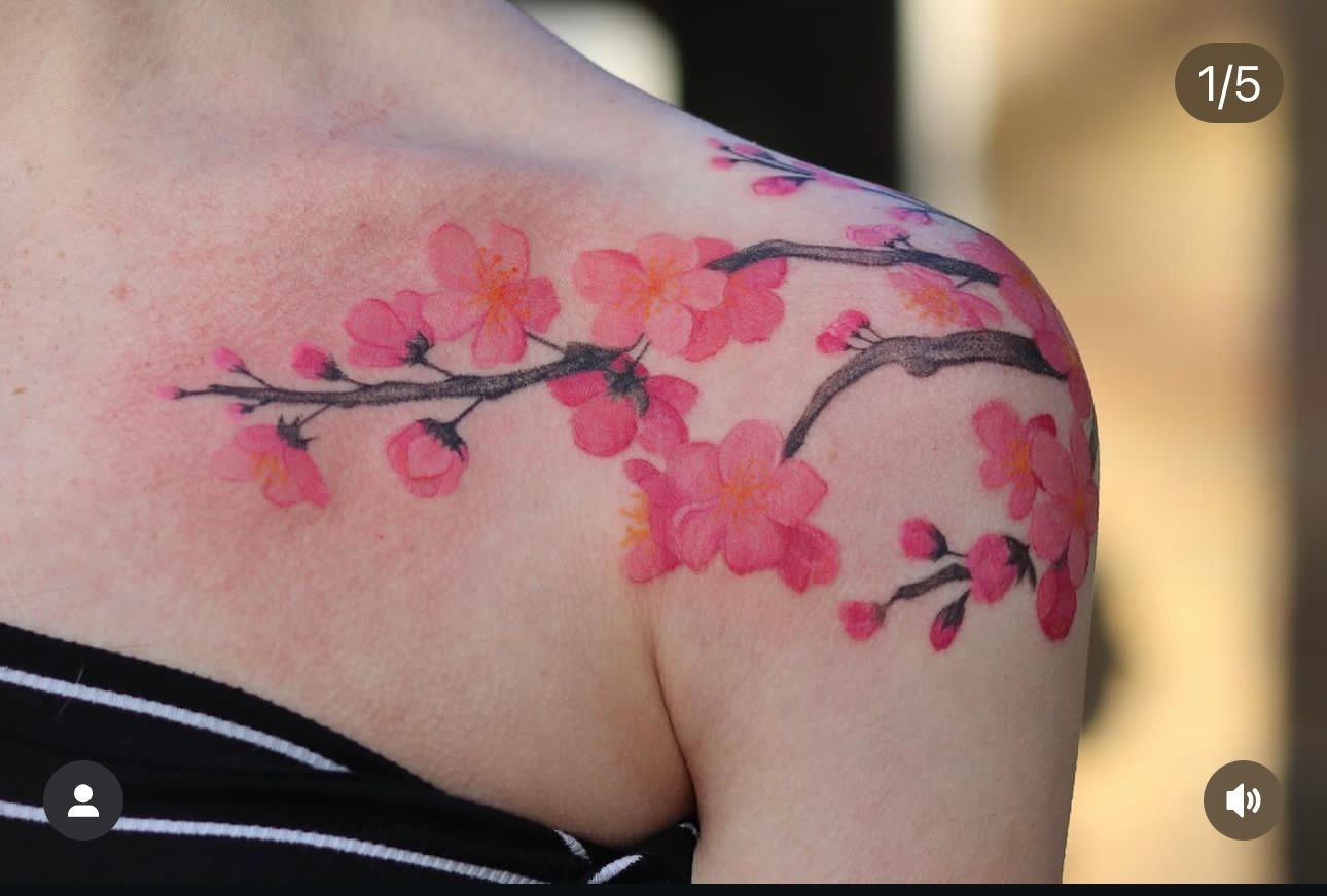 A woman has a tattoo of cherry blossoms on her shoulder