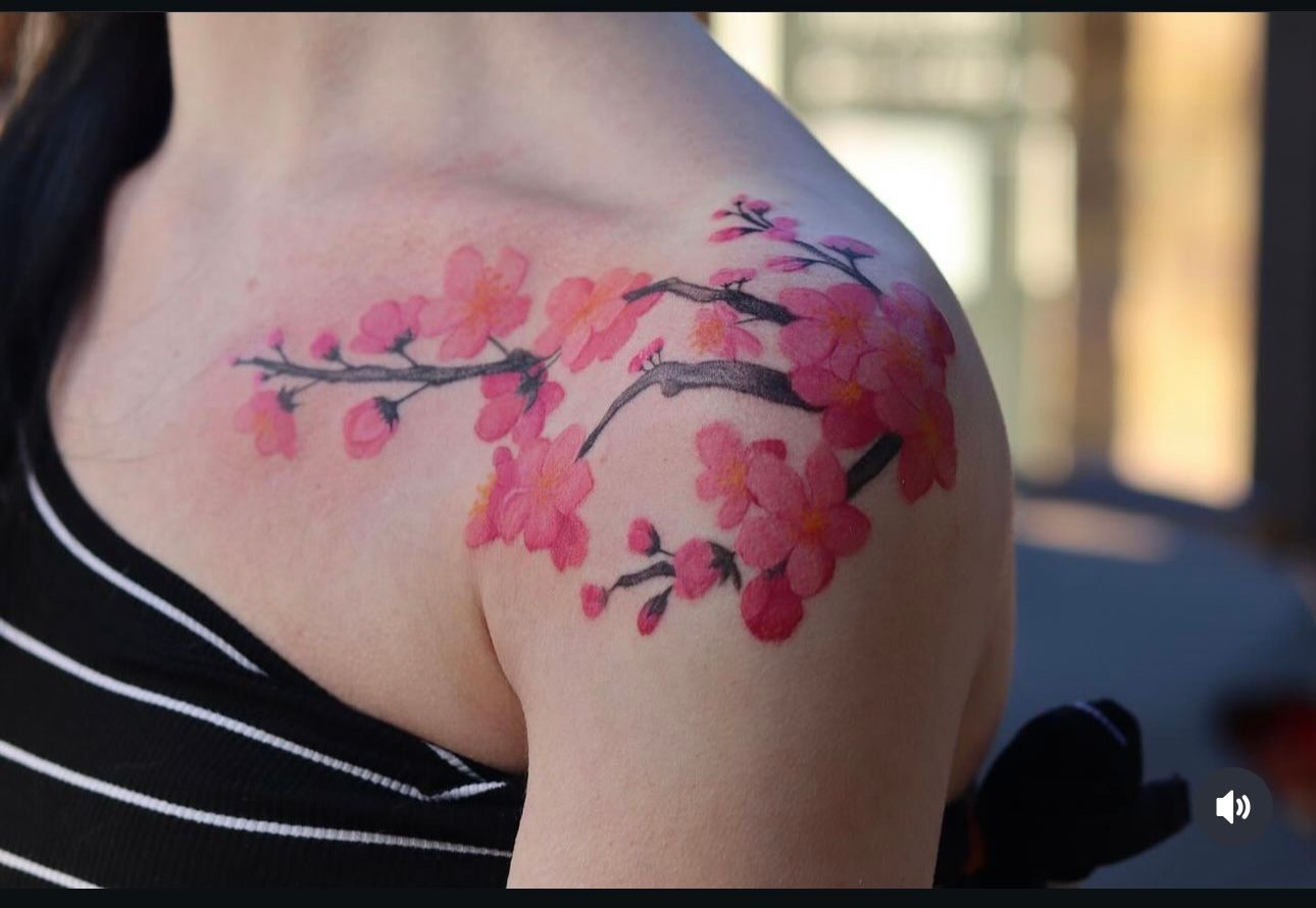 A woman has a tattoo of pink flowers on her shoulder