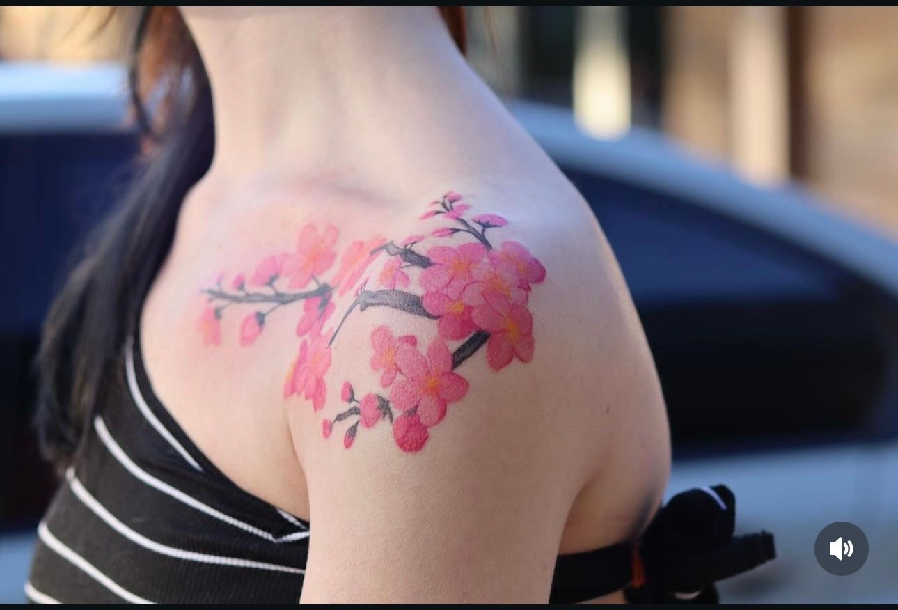 A woman has a tattoo of pink flowers on her shoulder