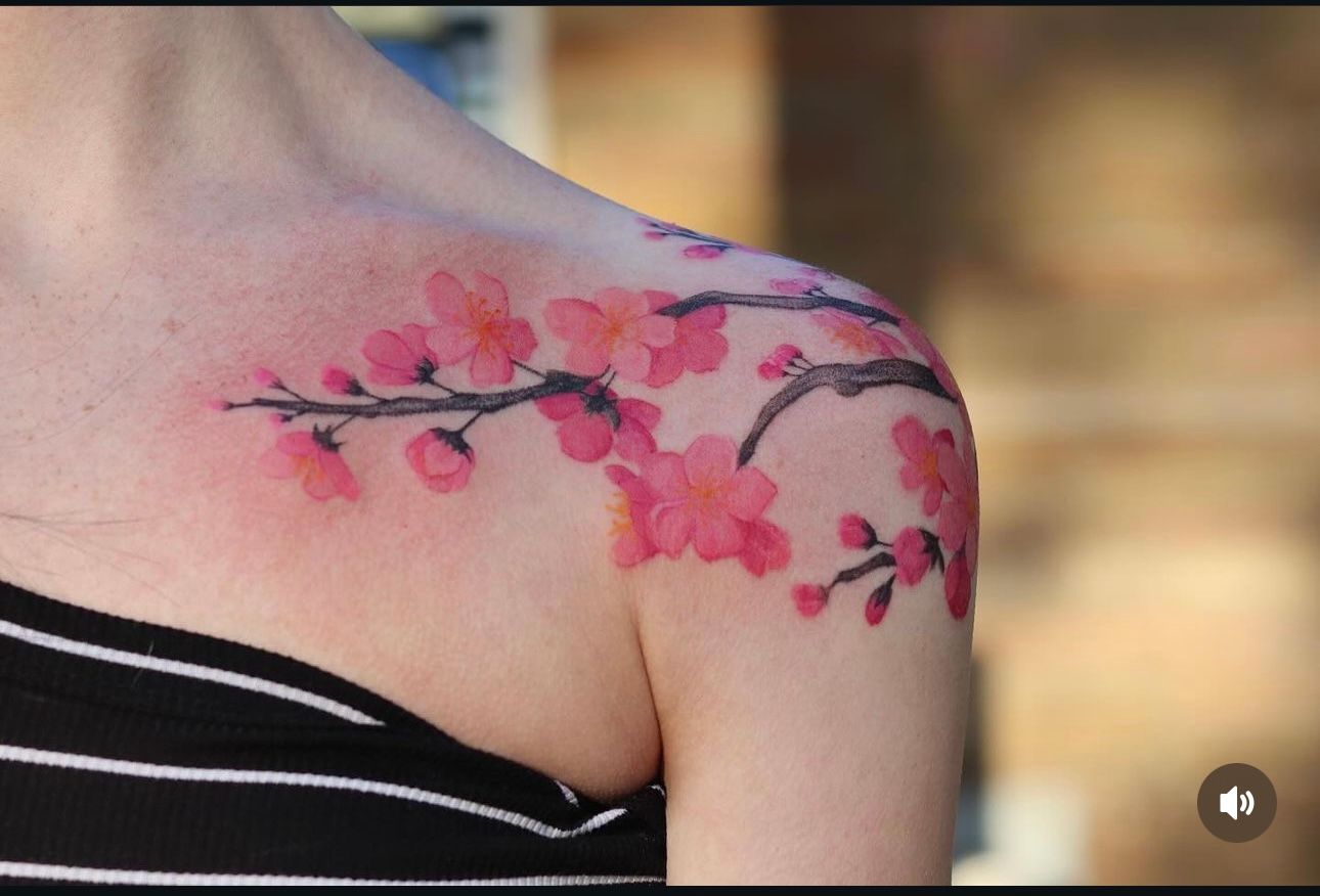 A woman has a cherry blossom tattoo on her shoulder