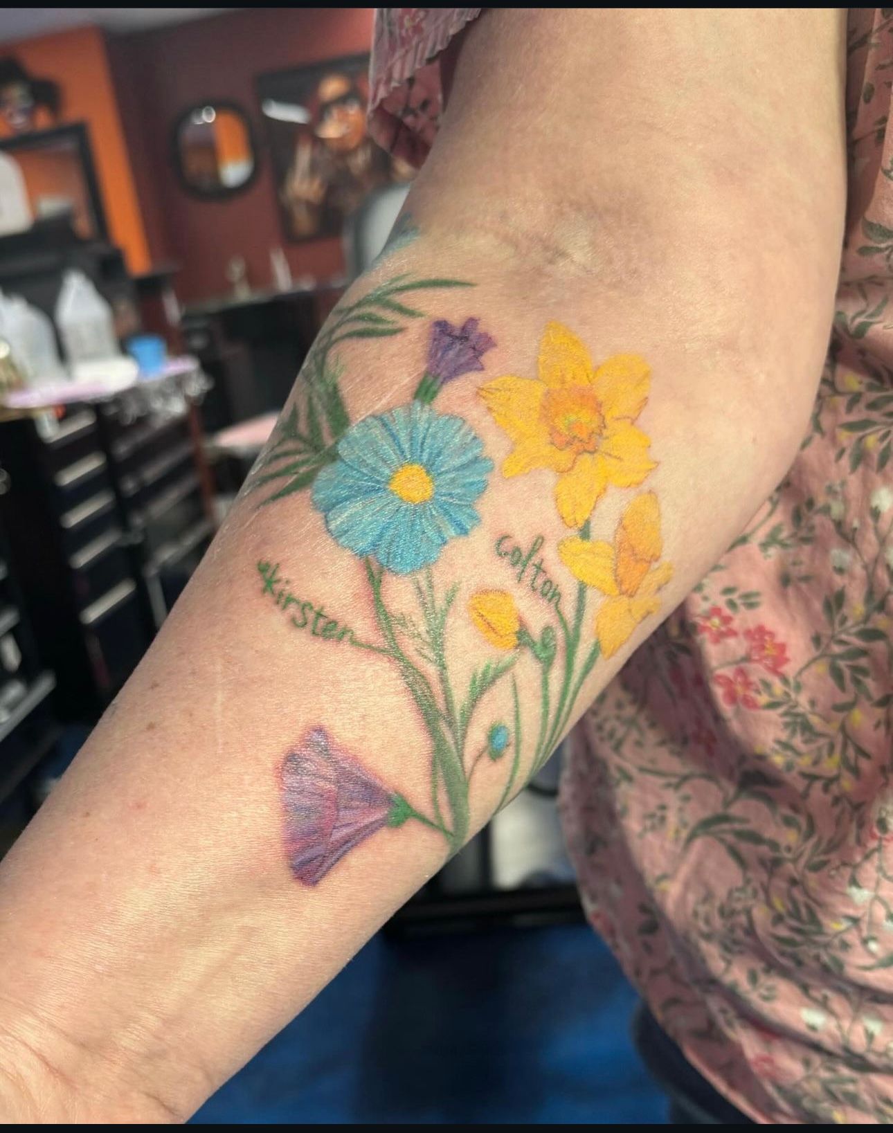 A woman has a tattoo of flowers on her forearm.