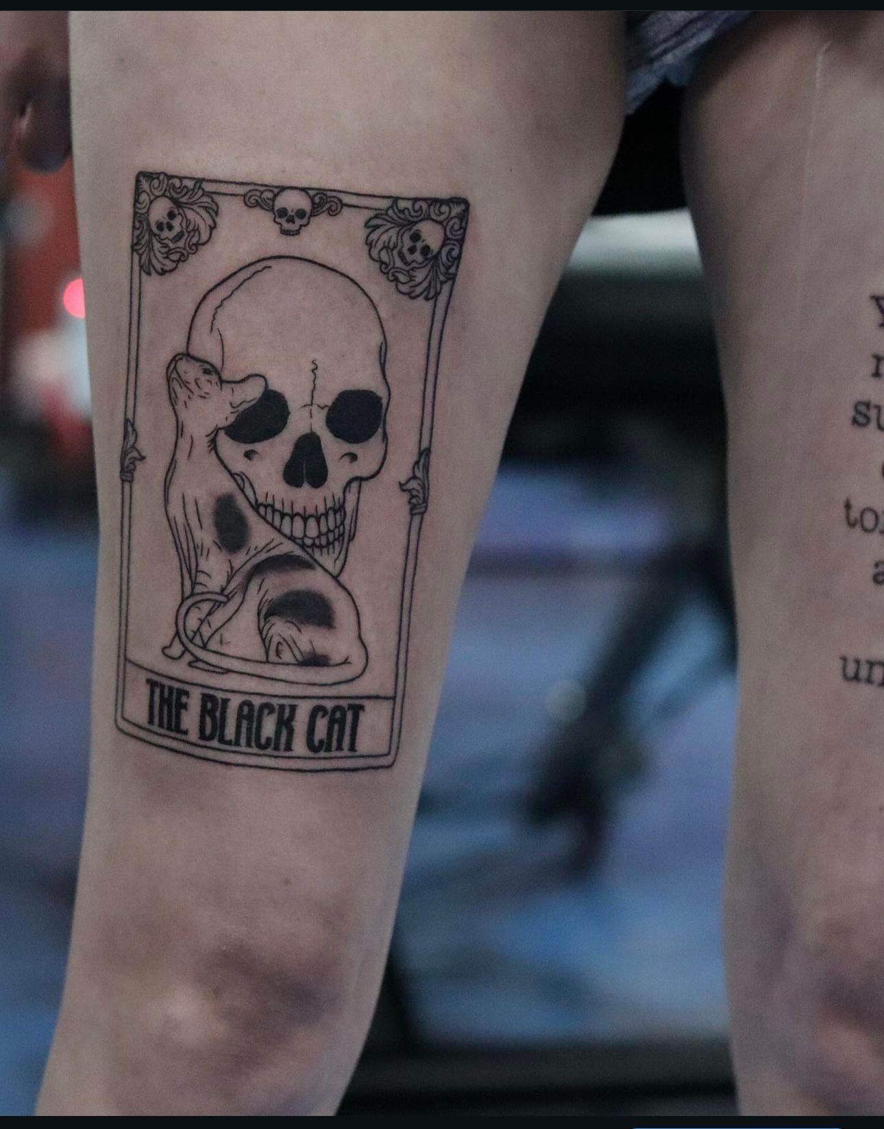 A person has a black cat tattoo on their leg
