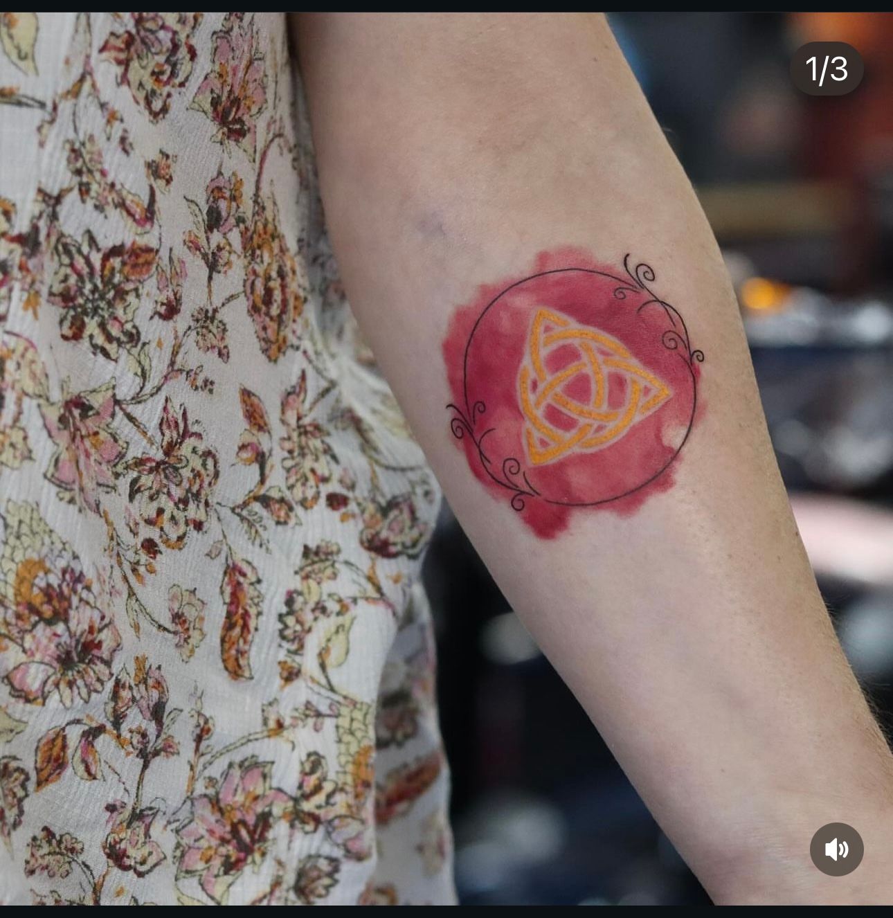 A woman has a tattoo of a triangle in a circle on her arm