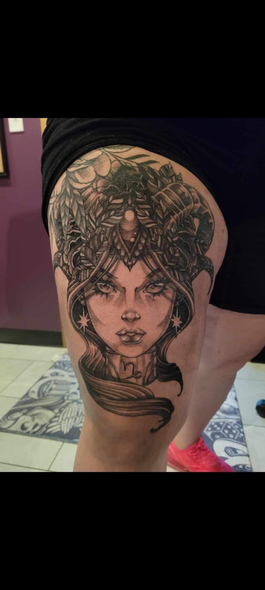 A woman has a medusa tattoo on her thigh.