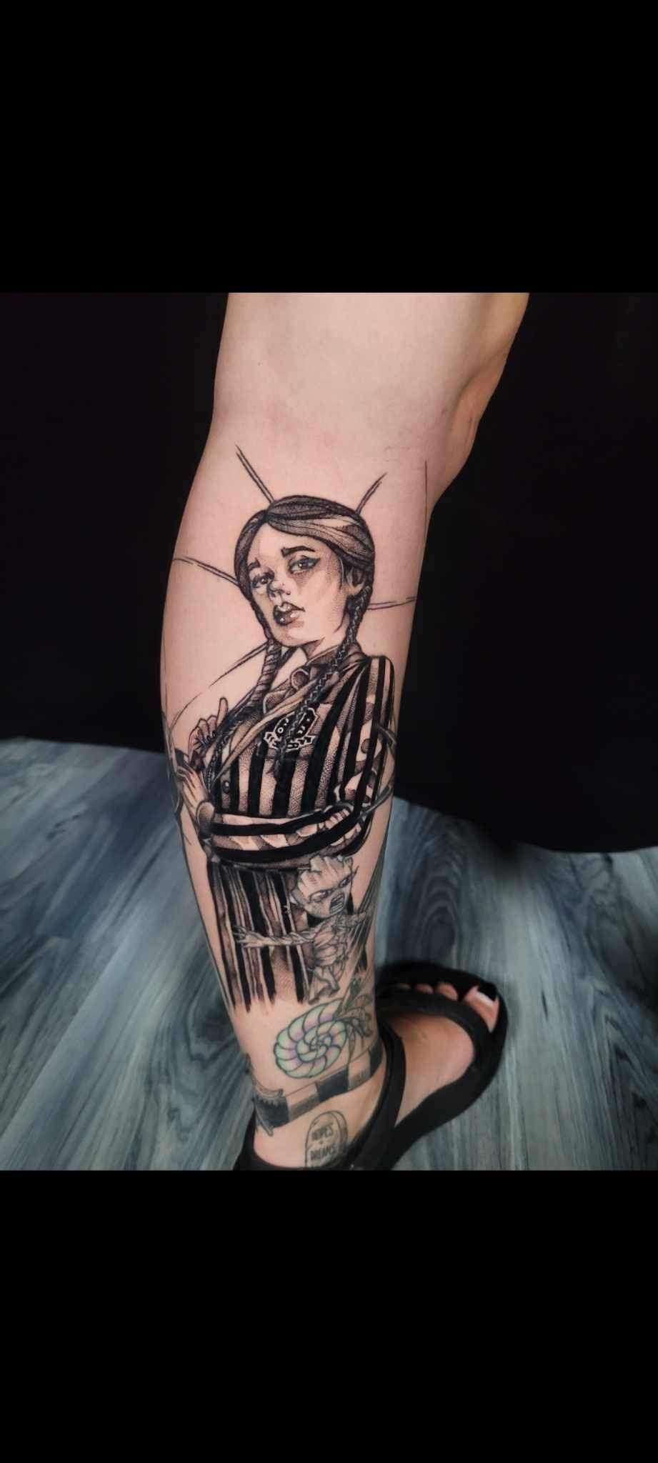 A person has a tattoo of a woman on their leg.