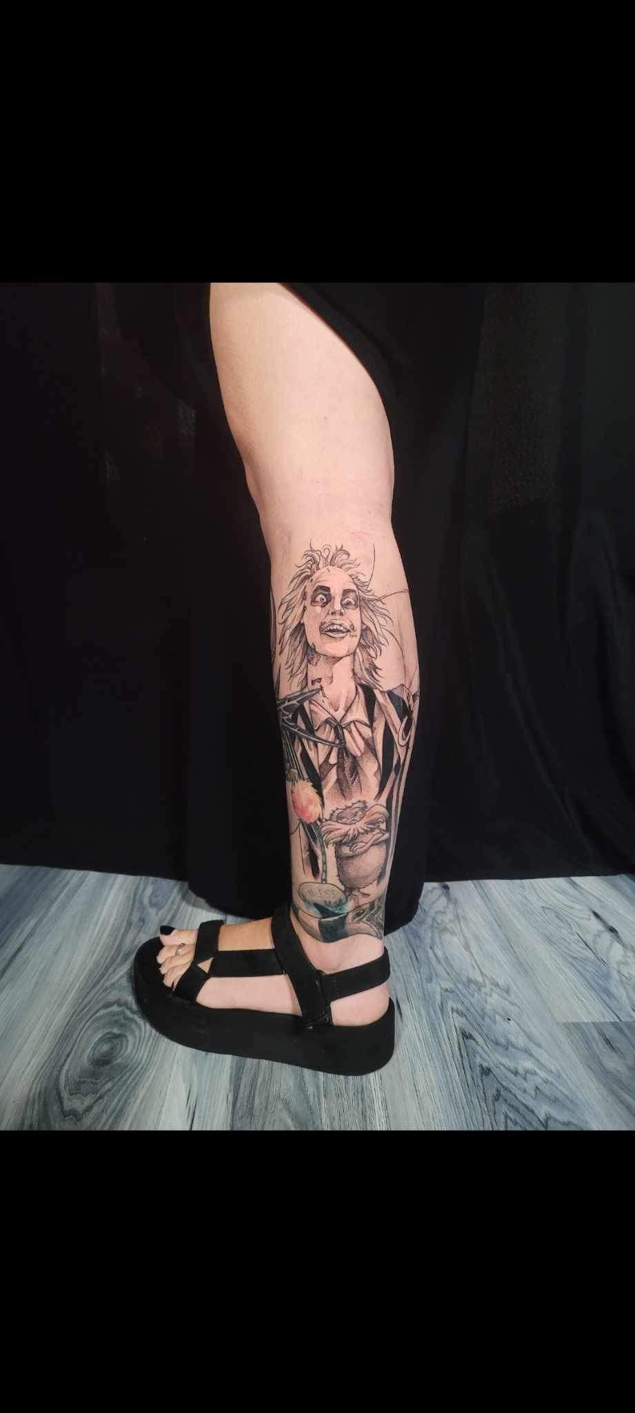 A person with a tattoo on their leg is wearing sandals.