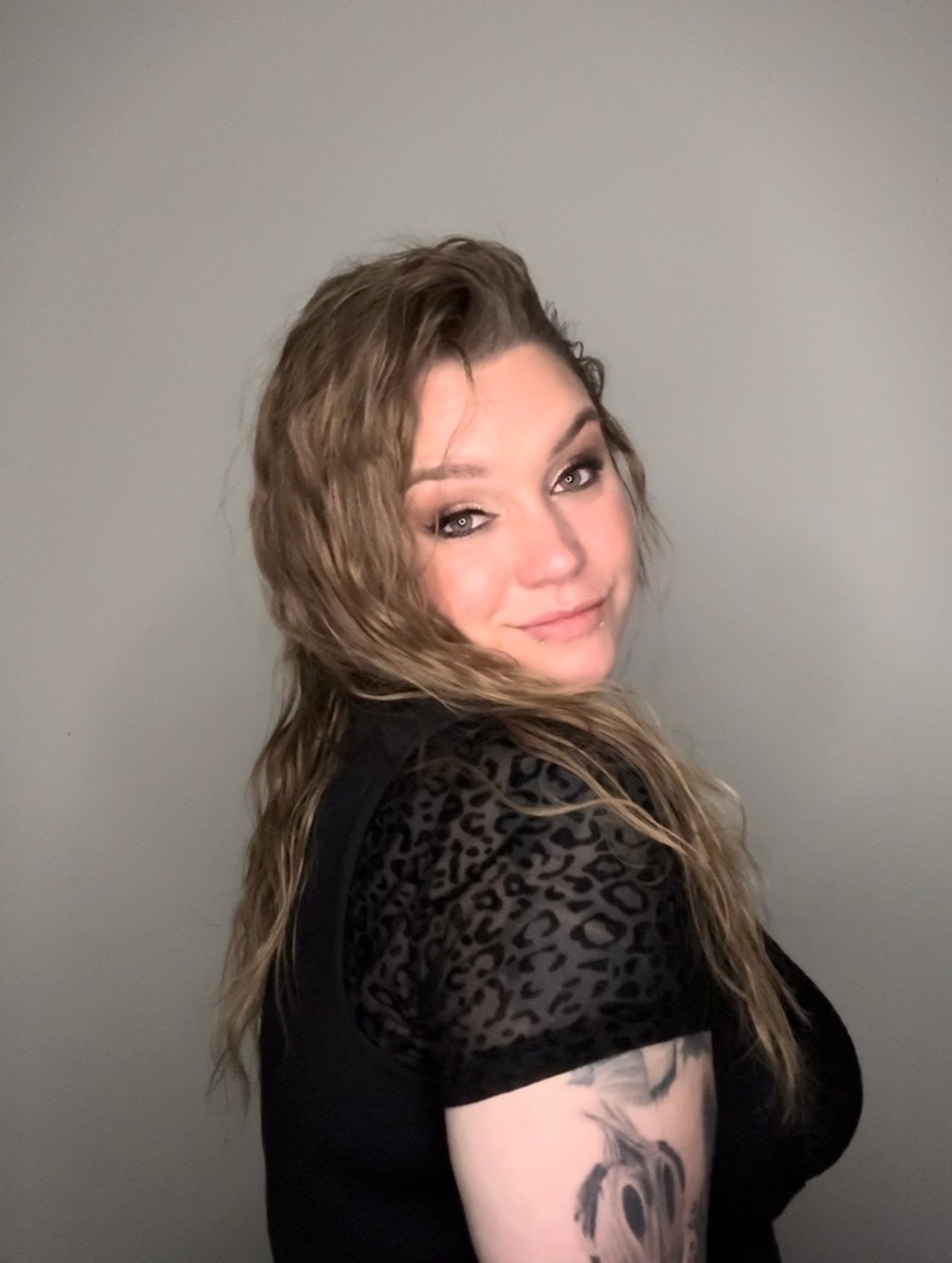 The woman is wearing a black shirt and has a tattoo on her arm.