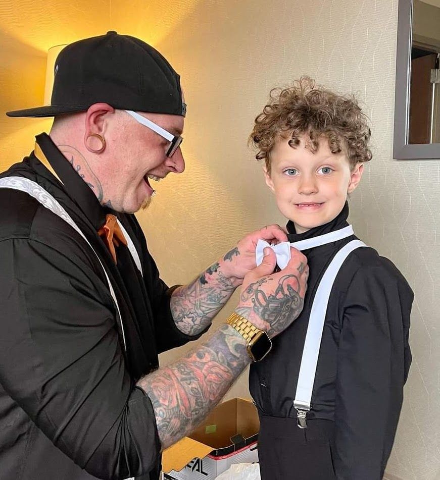 A man is helping a young boy tie his bow tie