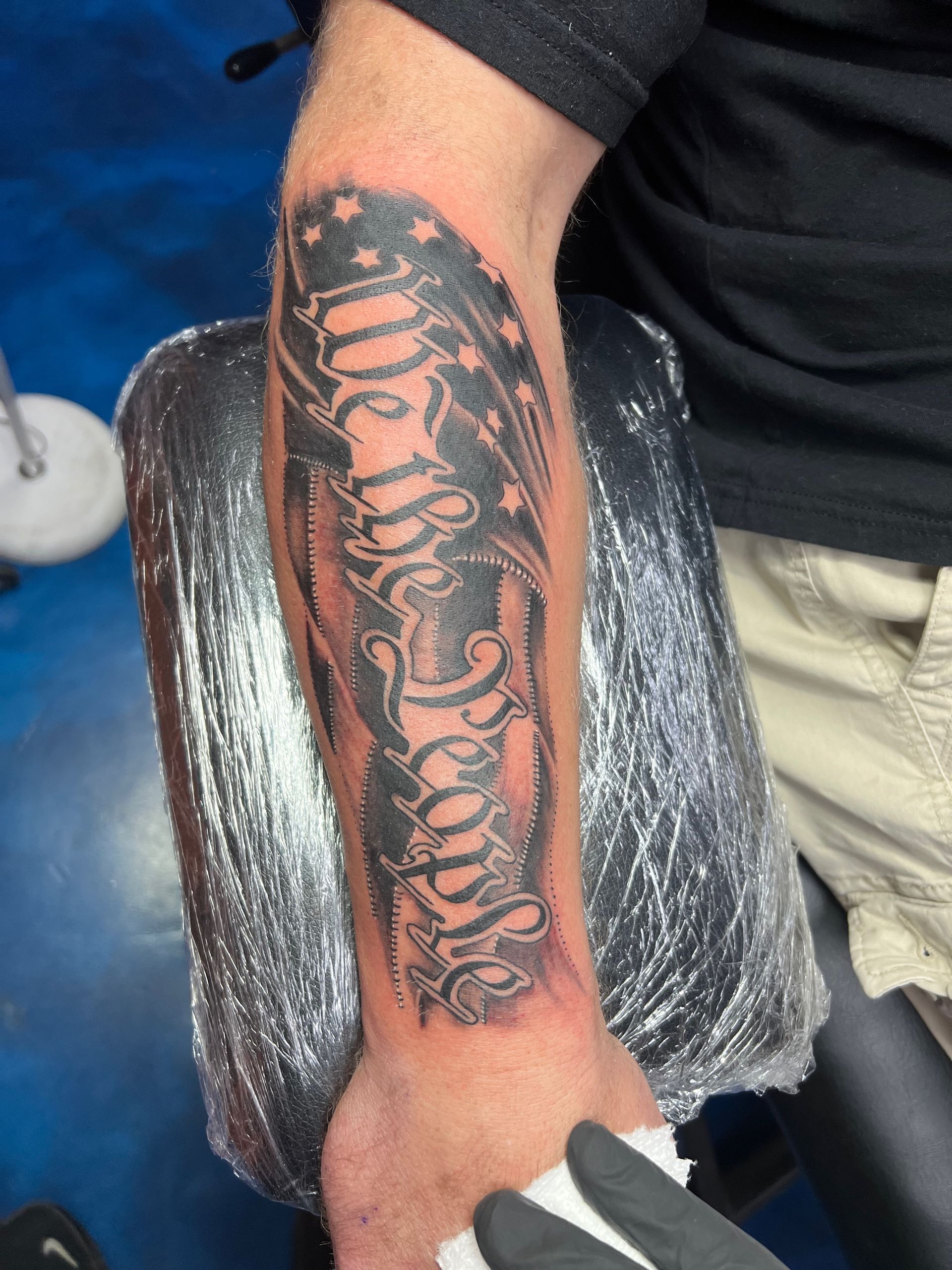 A man has a tattoo of we the people on his arm