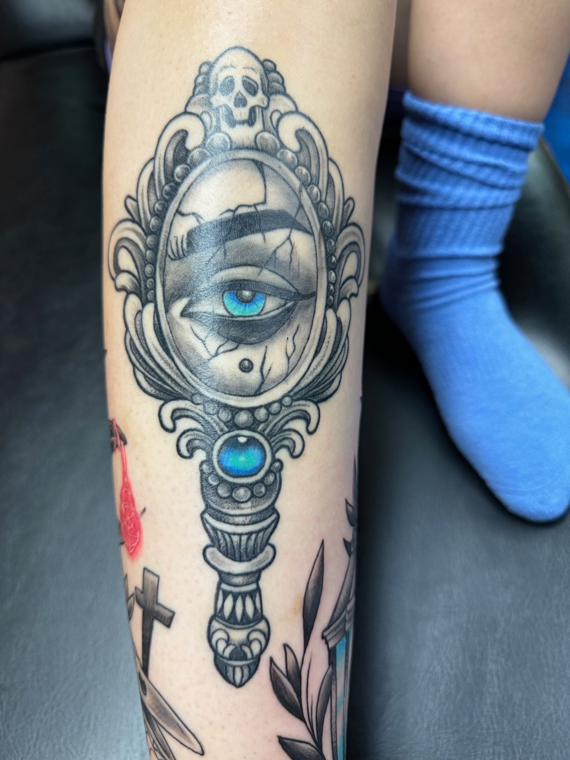 A person has a tattoo of a mirror with an eye in it